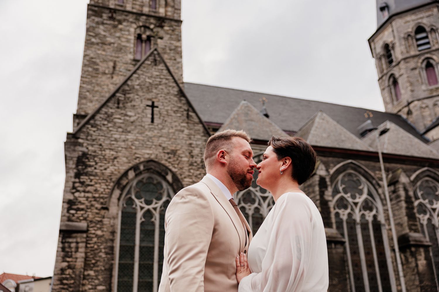 A couple embracing in front of a historic church building.