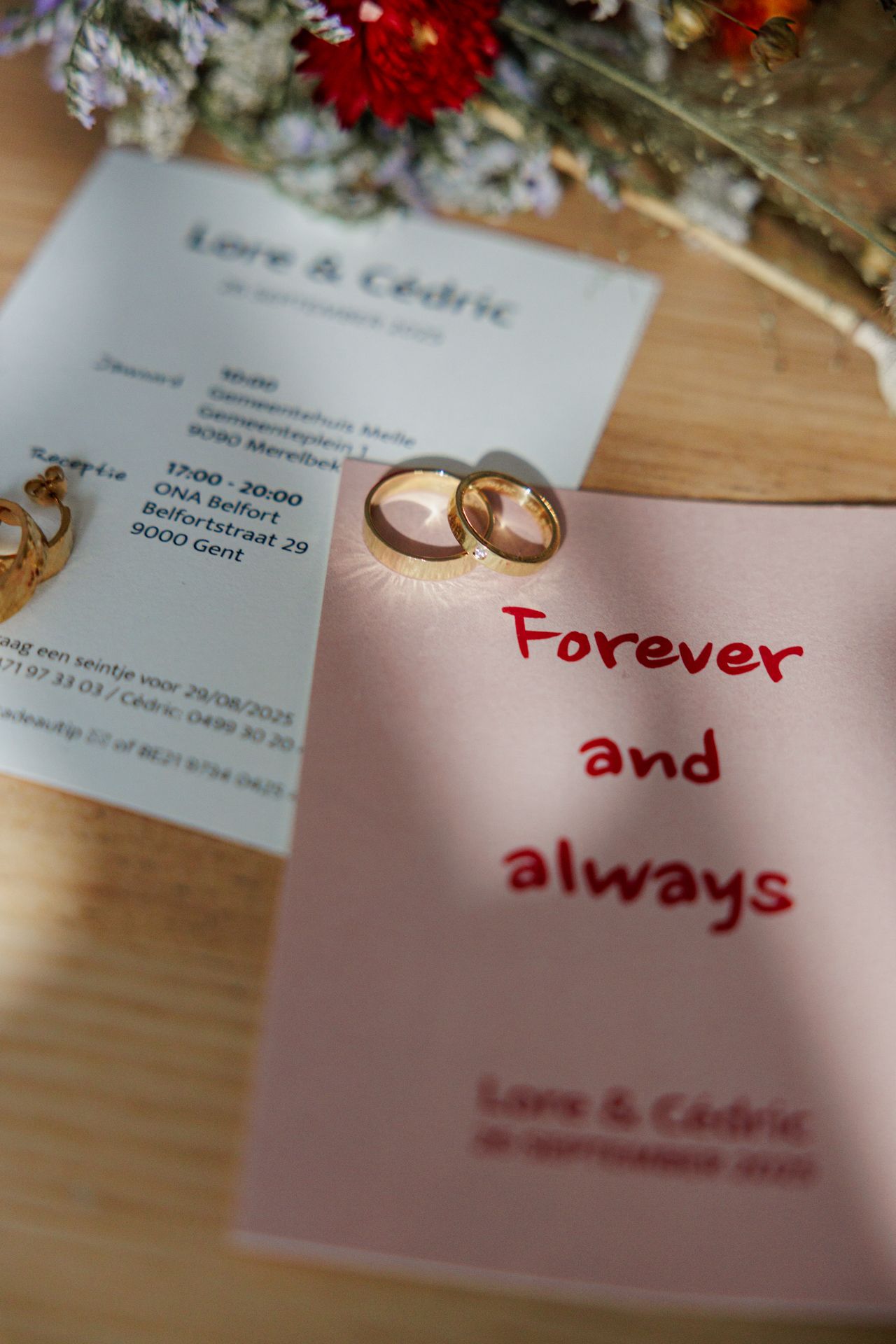 Two gold wedding rings on a card with the text 'Forever and always' and a wedding invitation.