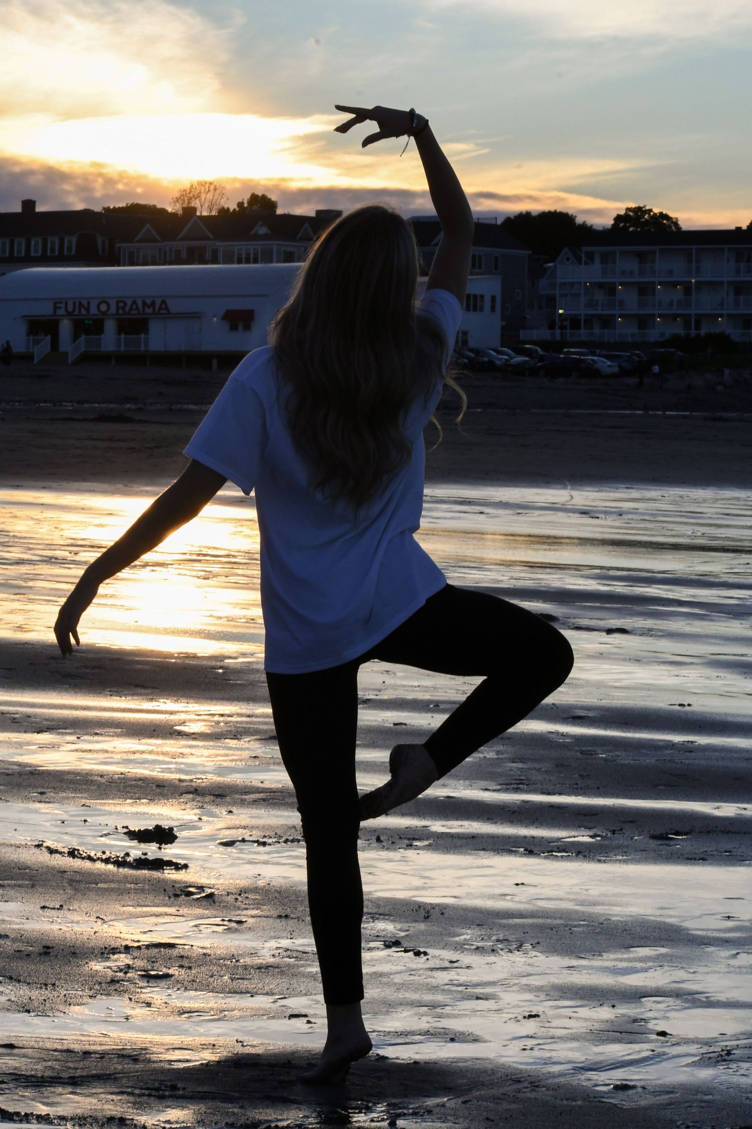 Silhouette of dancer in graceful pose against beach sunset.