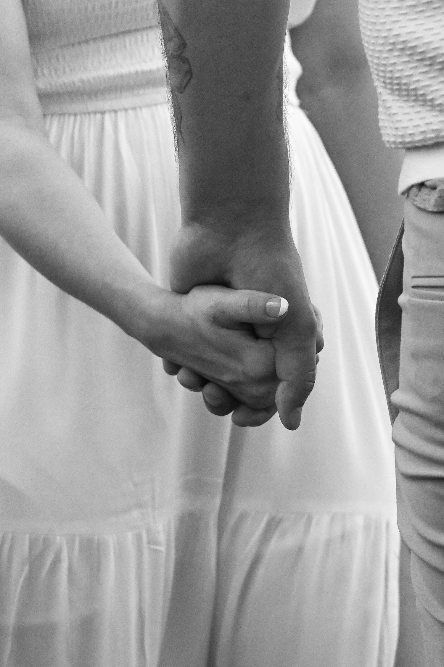 A series of black and white photos showing hands holding each other in different positions against white clothing.