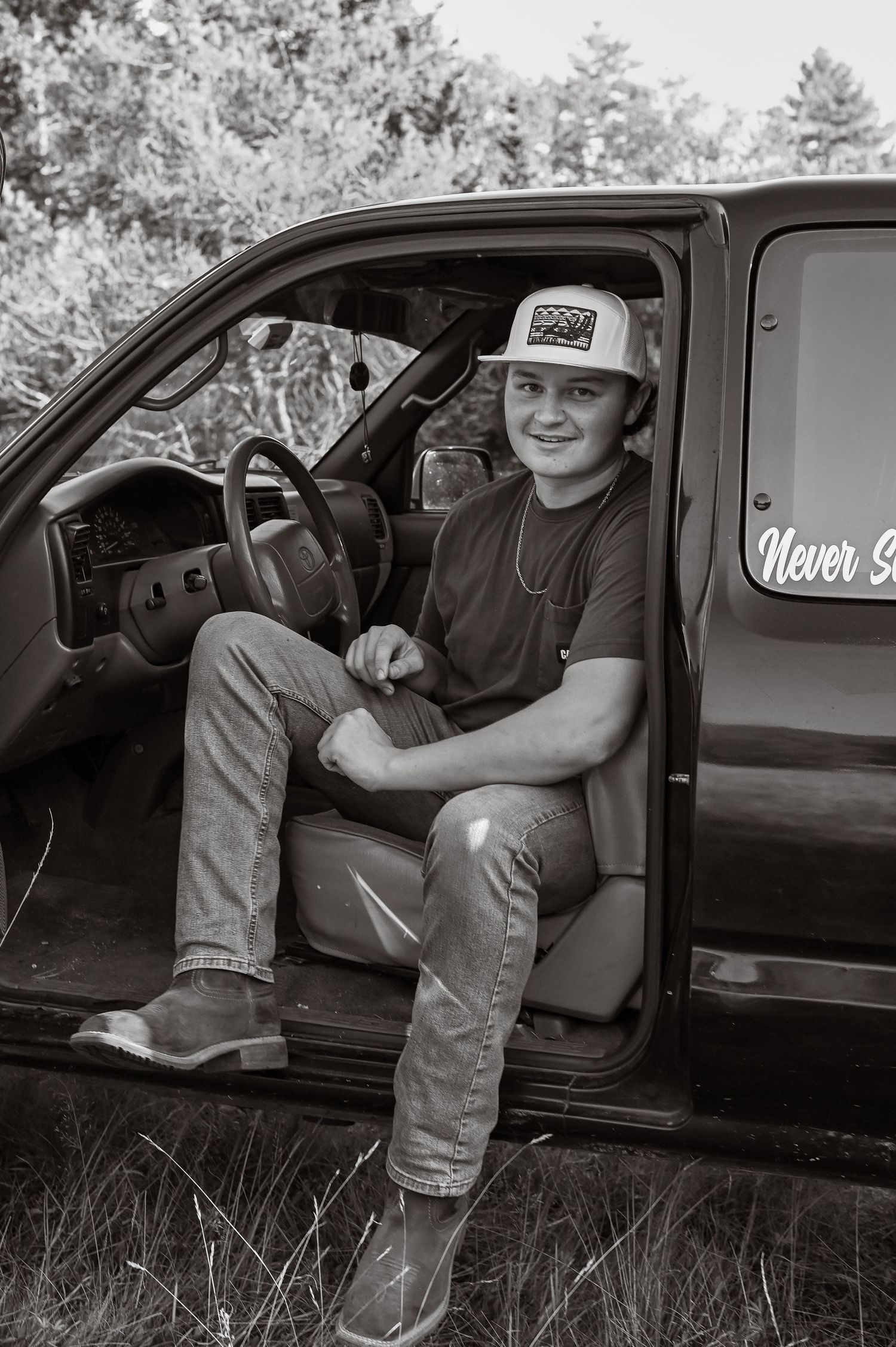 A series of black and white photos showing someone sitting in a truck wearing jeans and boots.