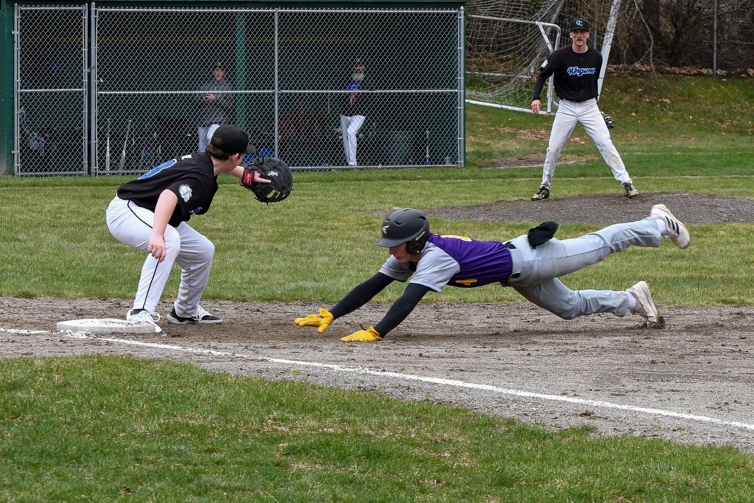 Baseball player sliding into first base during an intense play at the plate.