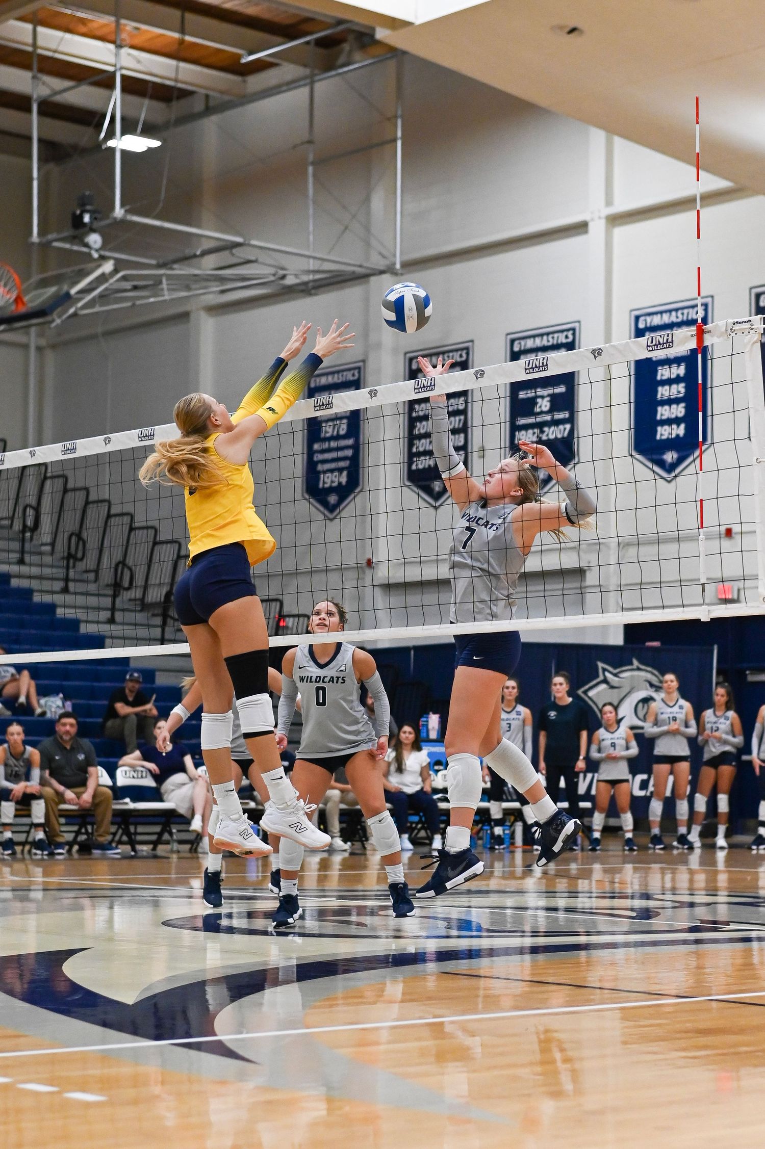 Volleyball players practice defensive diving drills during a training session in an indoor gymnasium.