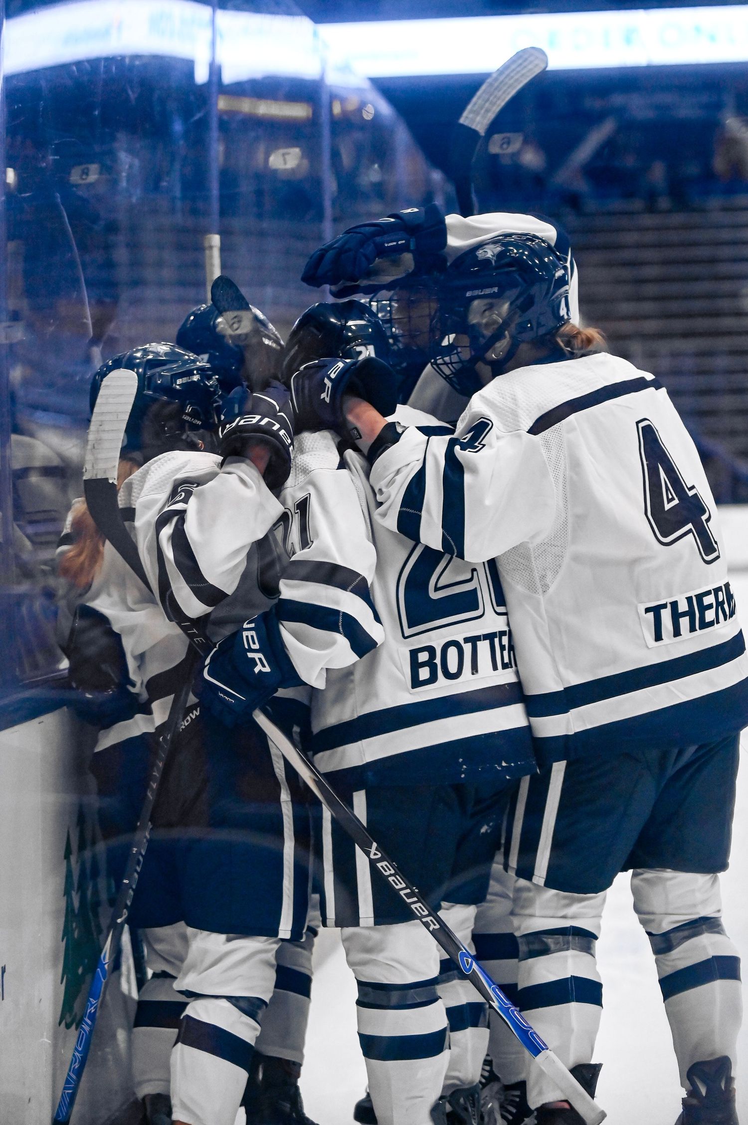 Hockey players in white and blue uniforms celebrate along the boards during an NHL game.