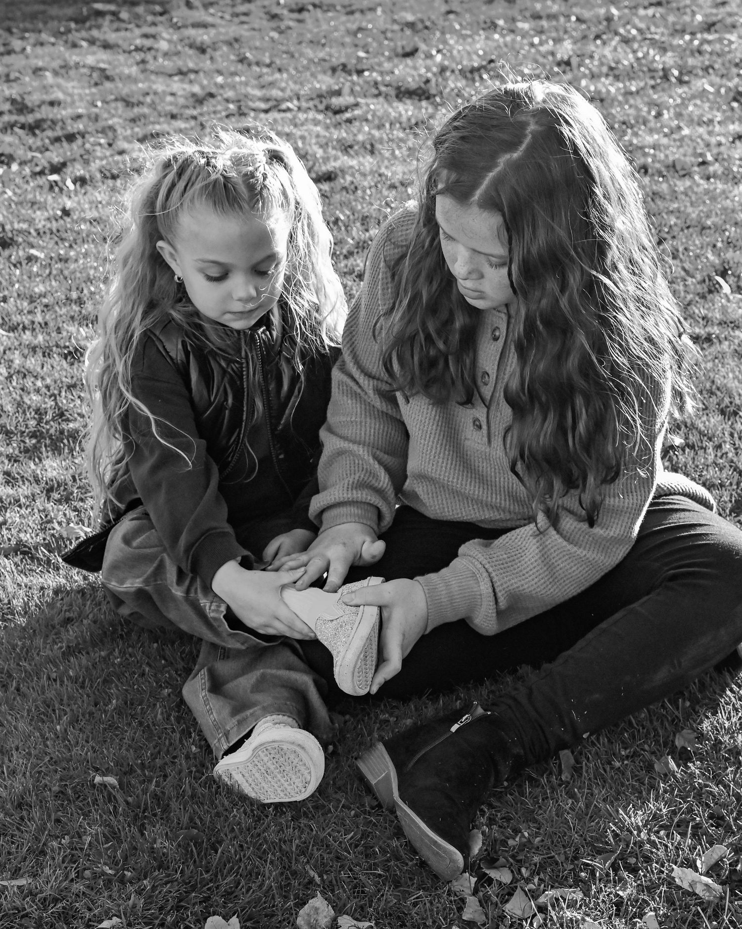 Two children sitting together on grass in black and white, shown in a series of candid moments.