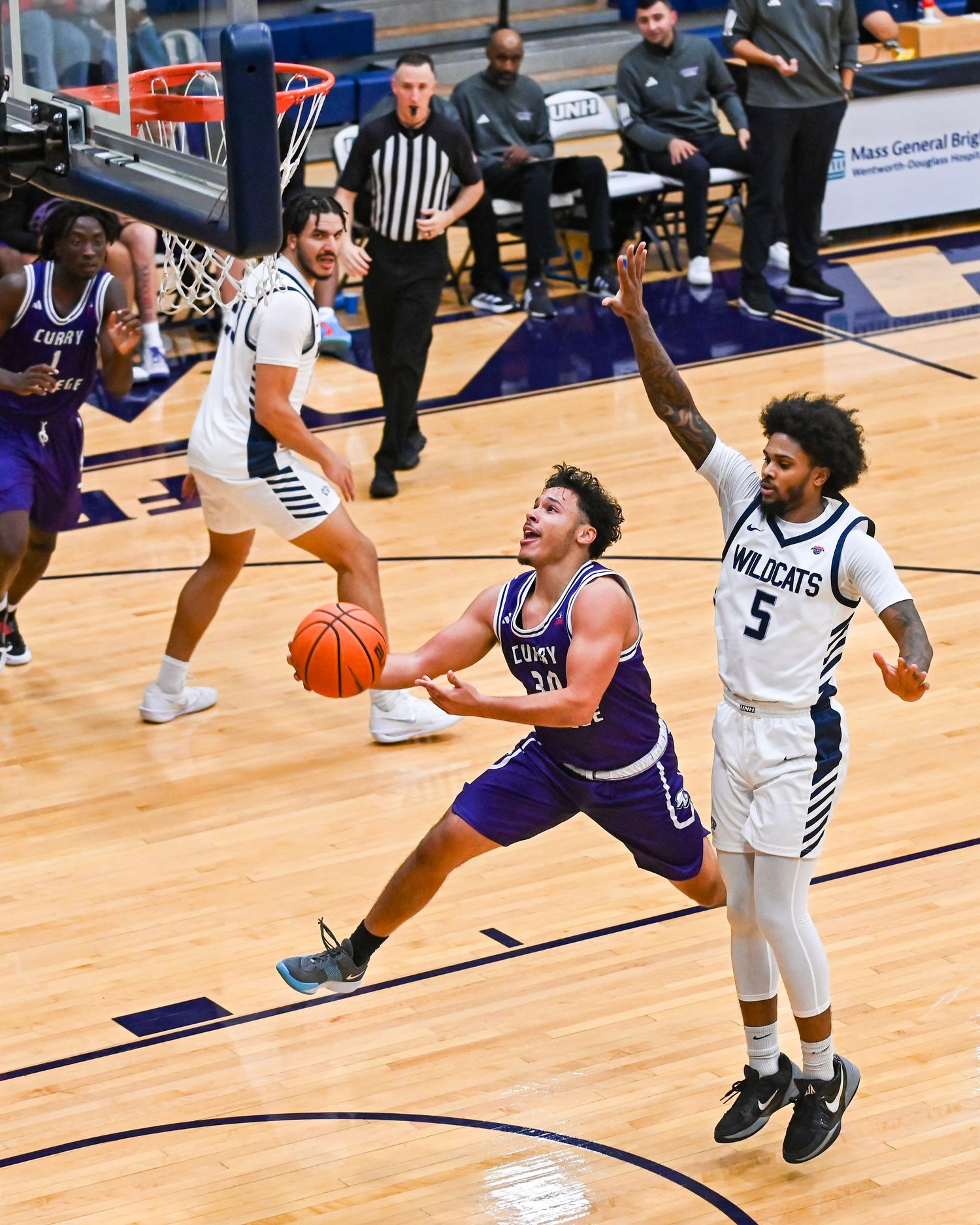 Basketball players compete for possession during an intense game on a wooden court.