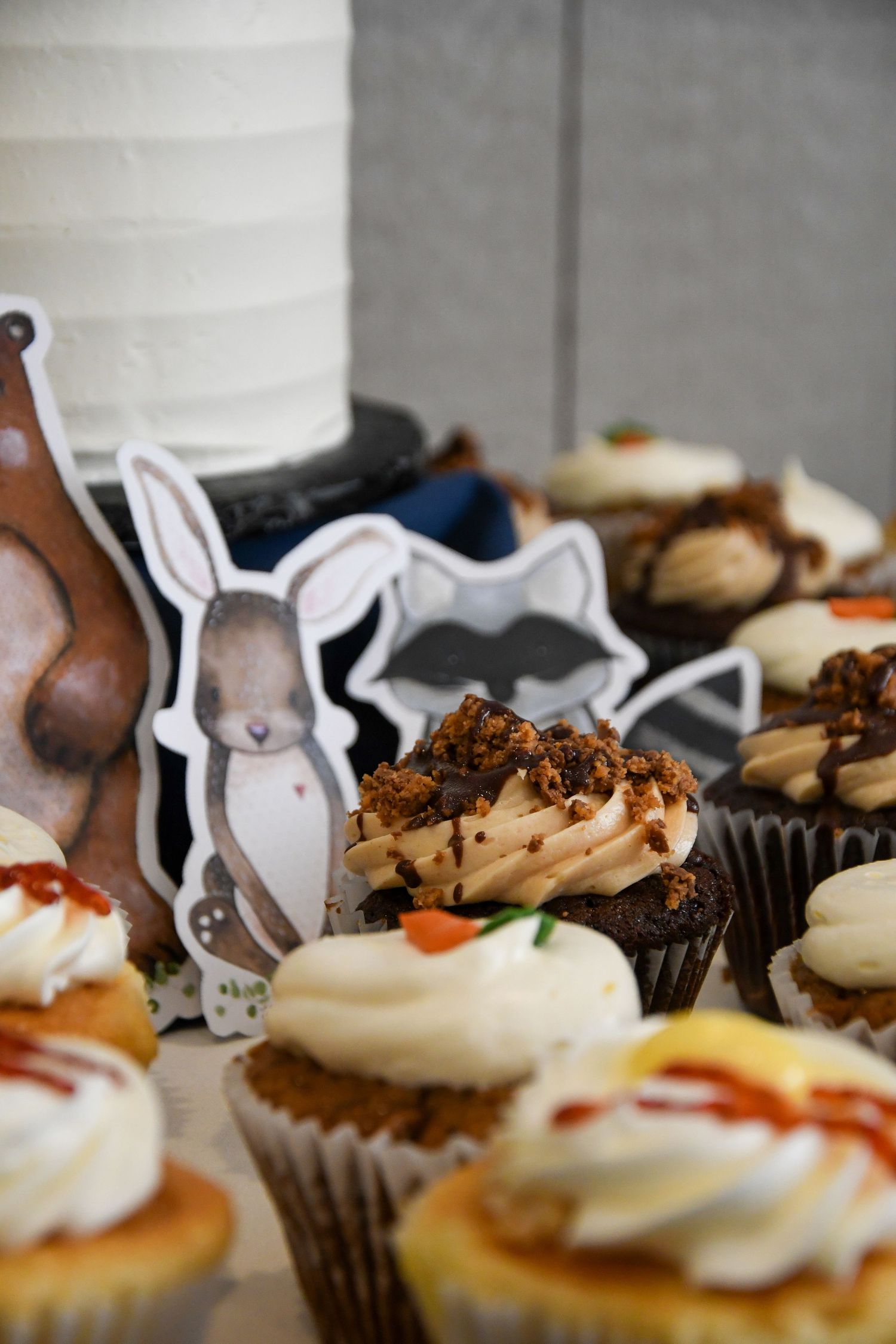 Decorated cupcakes with bunny-themed toppers displayed on dessert table.