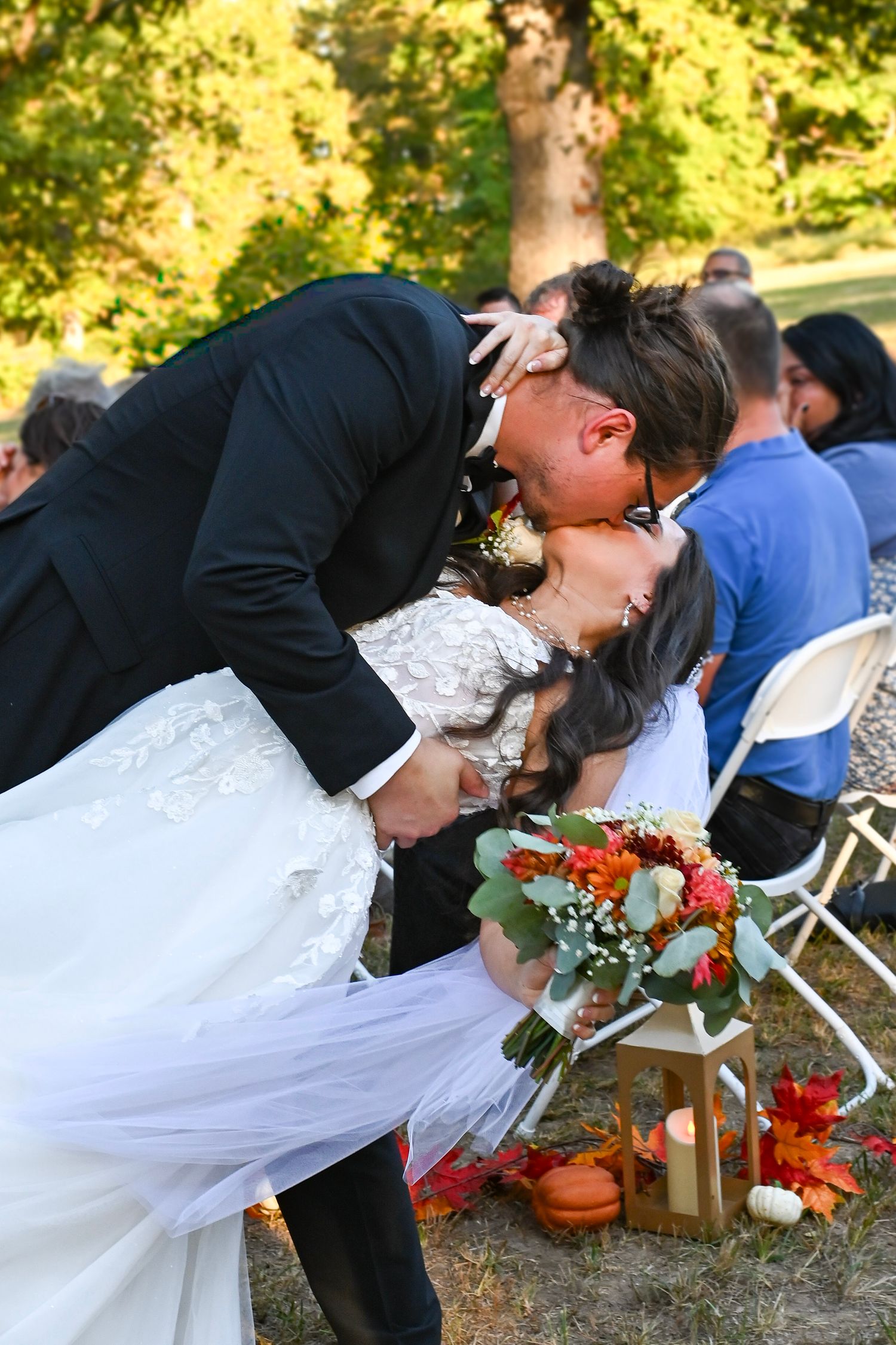 A romantic dip kiss sequence at an outdoor autumn wedding with orange flowers and fall decor.