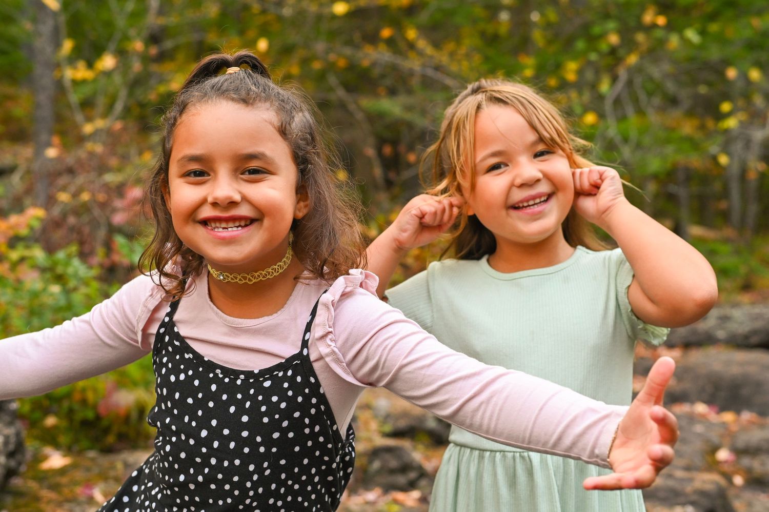 Children playing and smiling together outdoors in a natural setting during autumn.