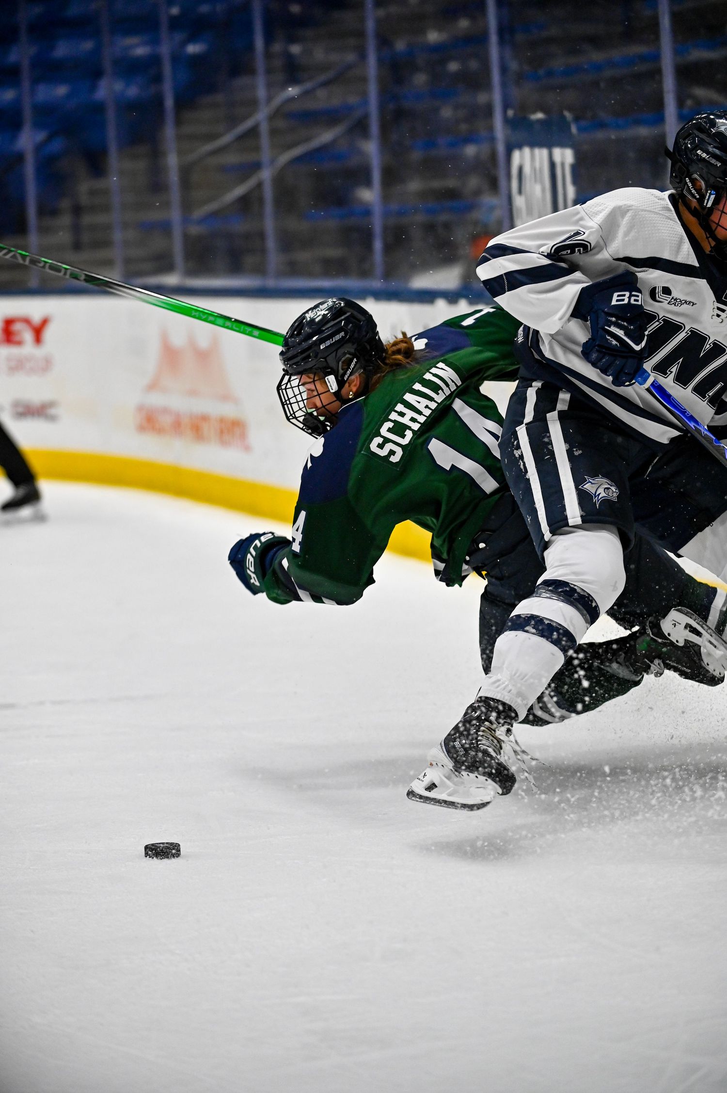 Hockey players dive and stretch across the ice to chase after a loose puck during an intense game sequence.