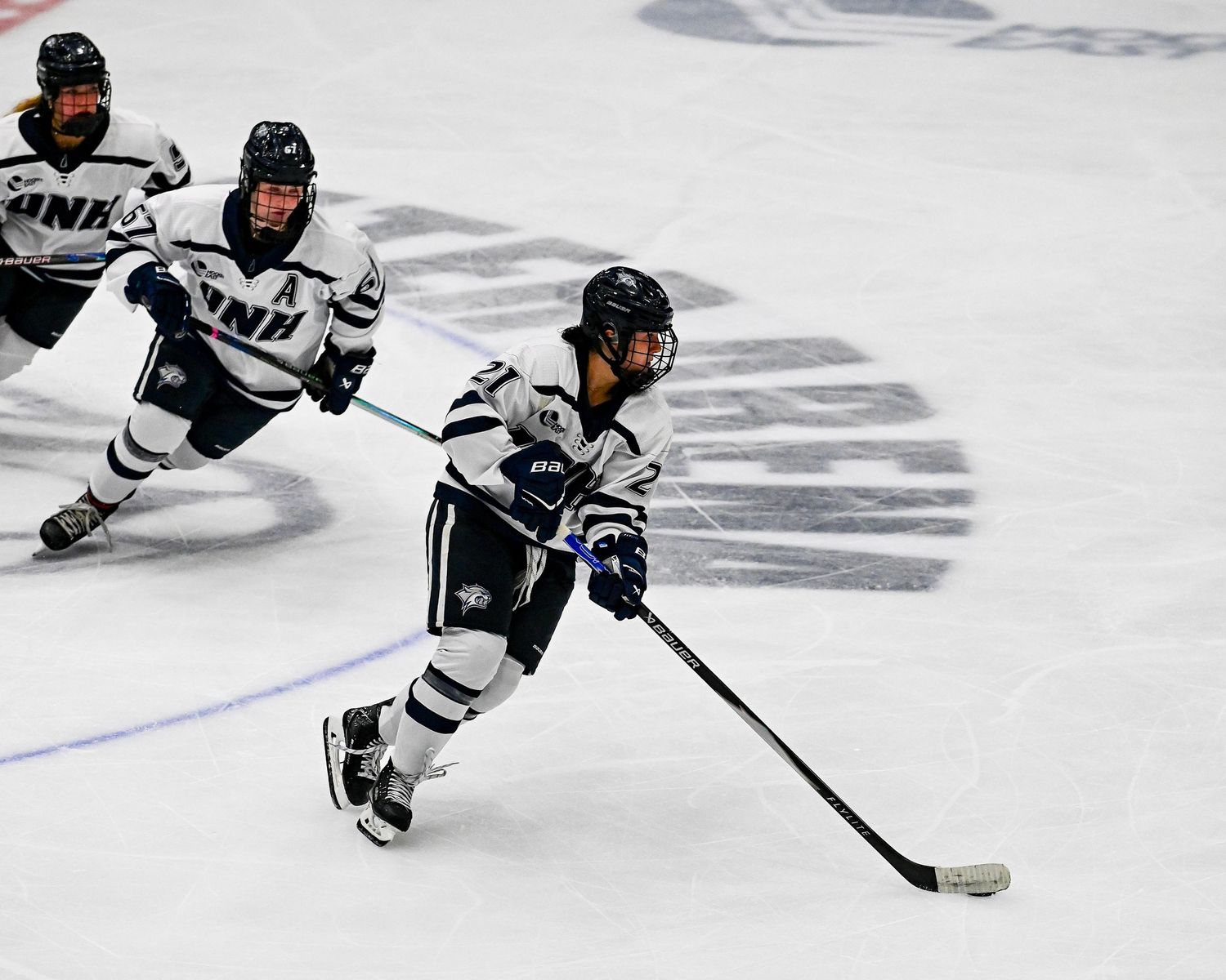 Hockey players in black and white uniforms compete for the puck during an intense game on the ice.