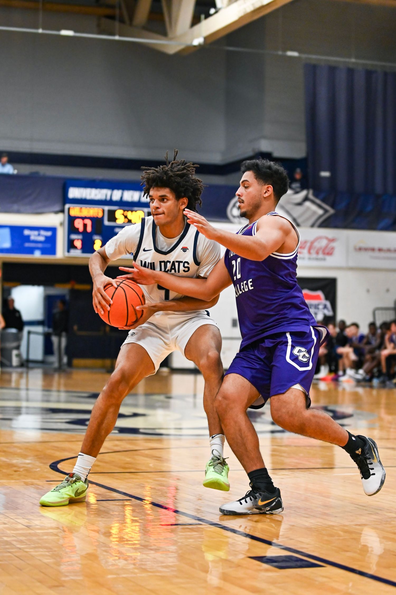 Basketball players from opposing teams collide and fall during an intense game on the hardwood court.