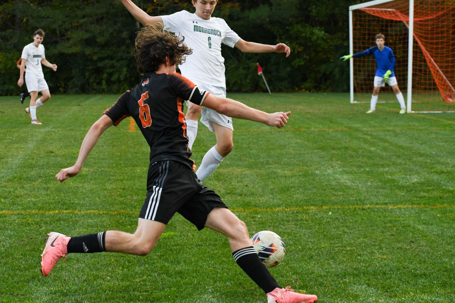 Soccer players from opposing teams battling for ball control during match.