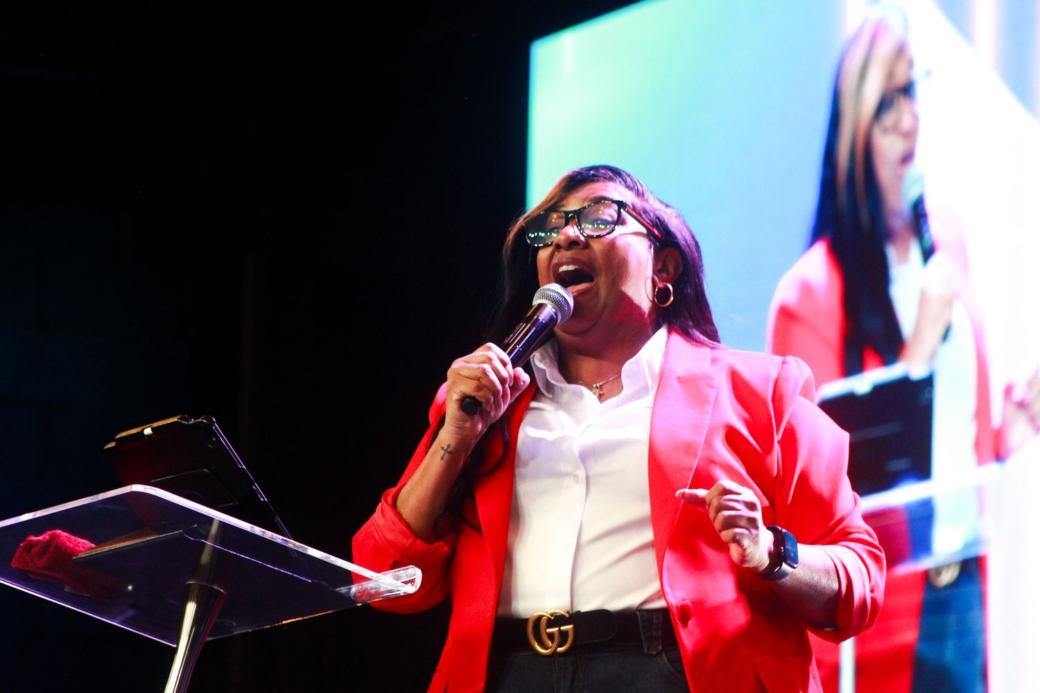Performance shots showing someone preaching on stage with bright lighting and red attire.