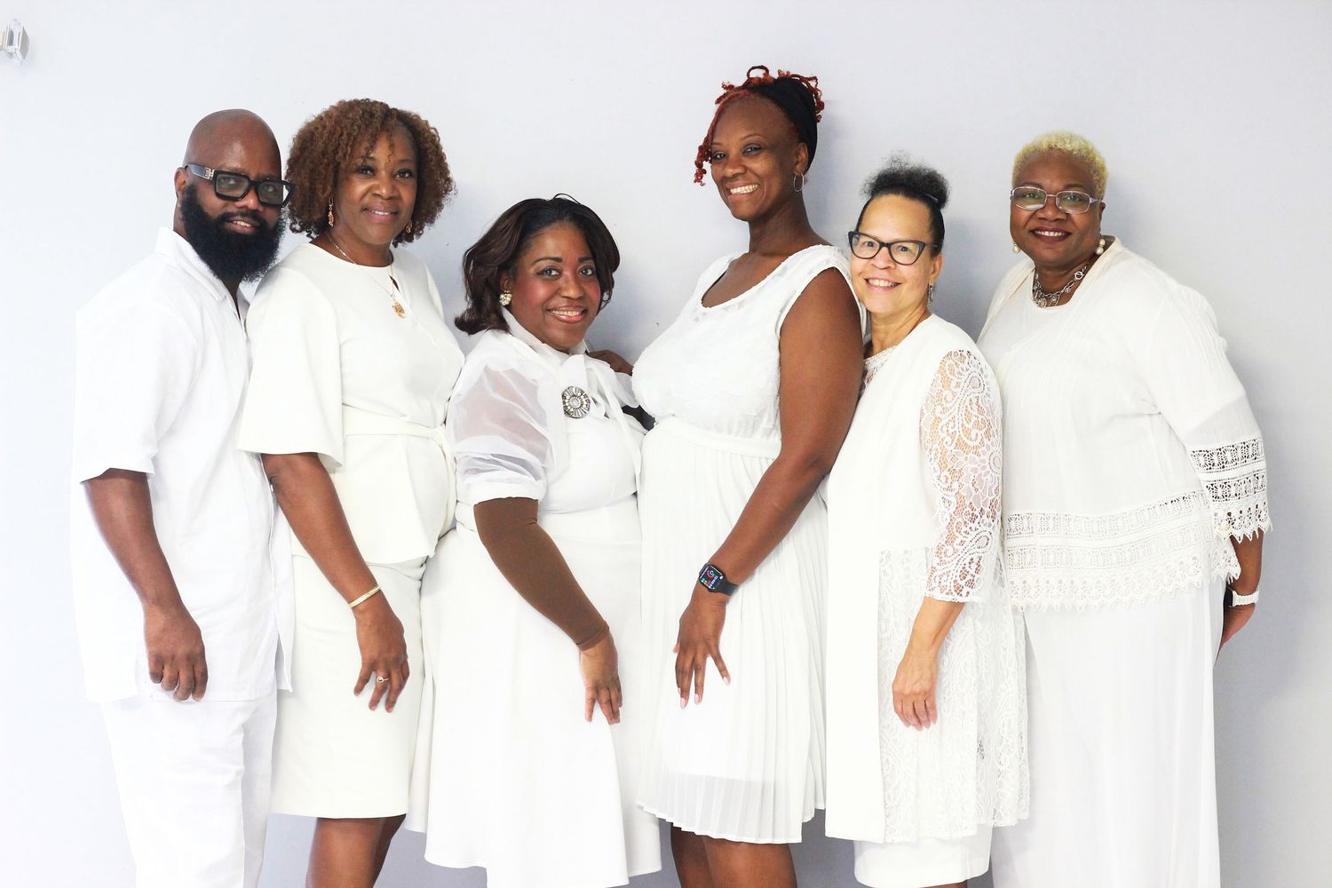 Group photo of people wearing matching white outfits against a white background.