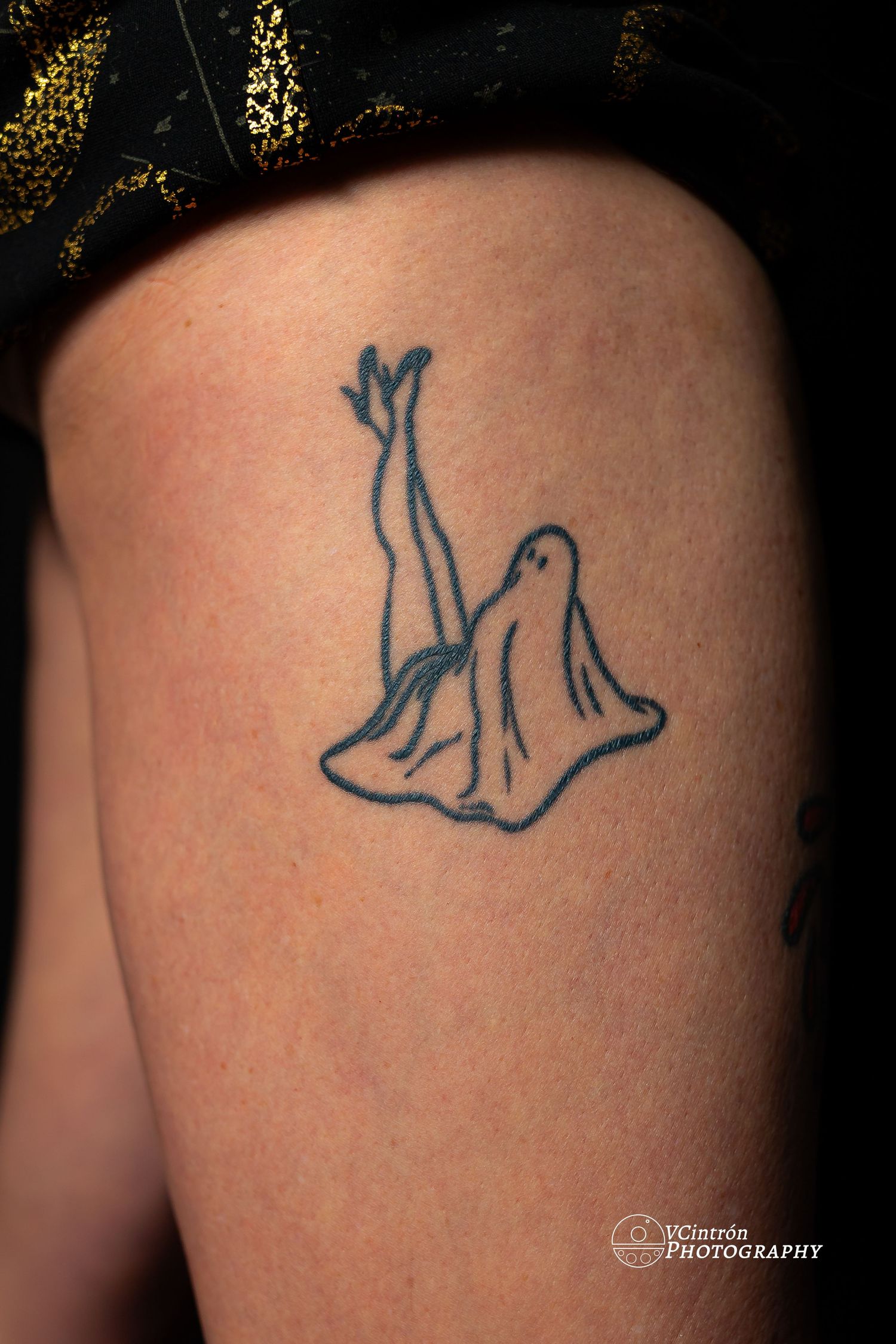 Simple black line tattoo of a seated figure with legs raised drawn in a minimalist style on skin.