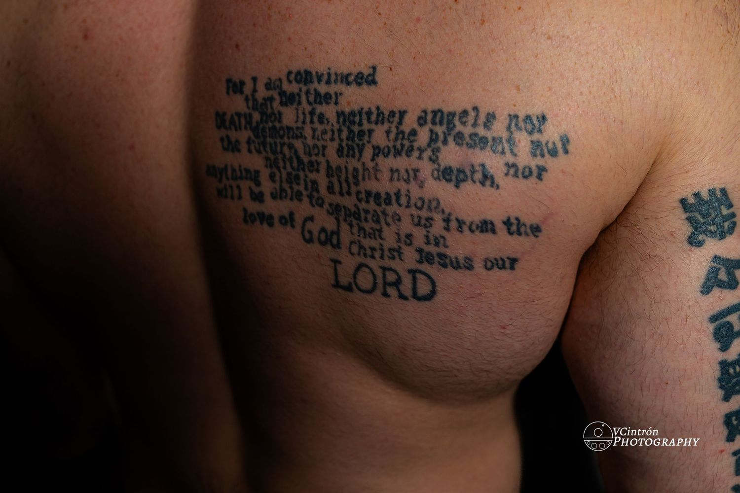 Religious scripture verse tattoo in black ink across someone's chest in a minimalist text design style.