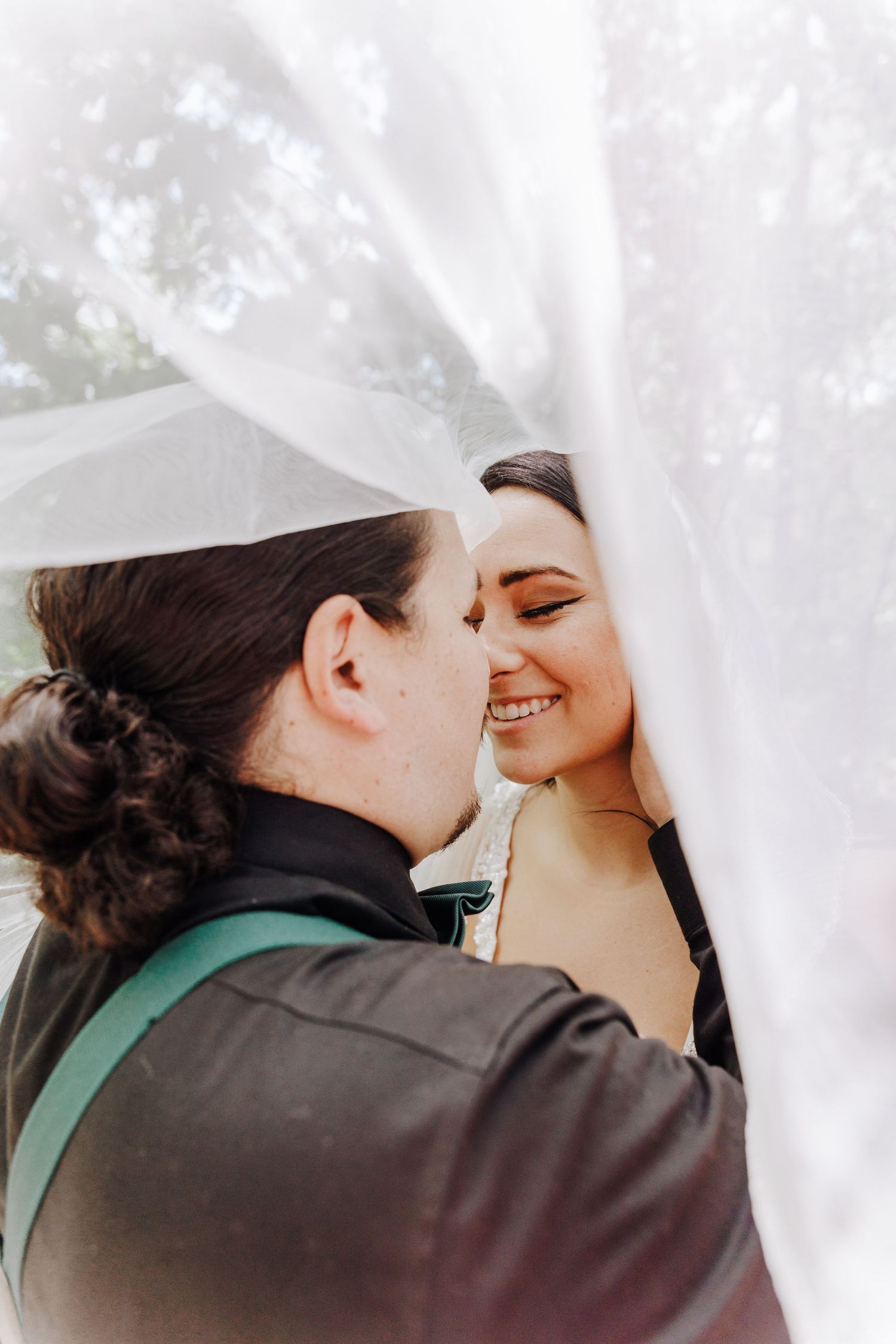 An intimate moment under a flowing white veil captured during a wedding ceremony.