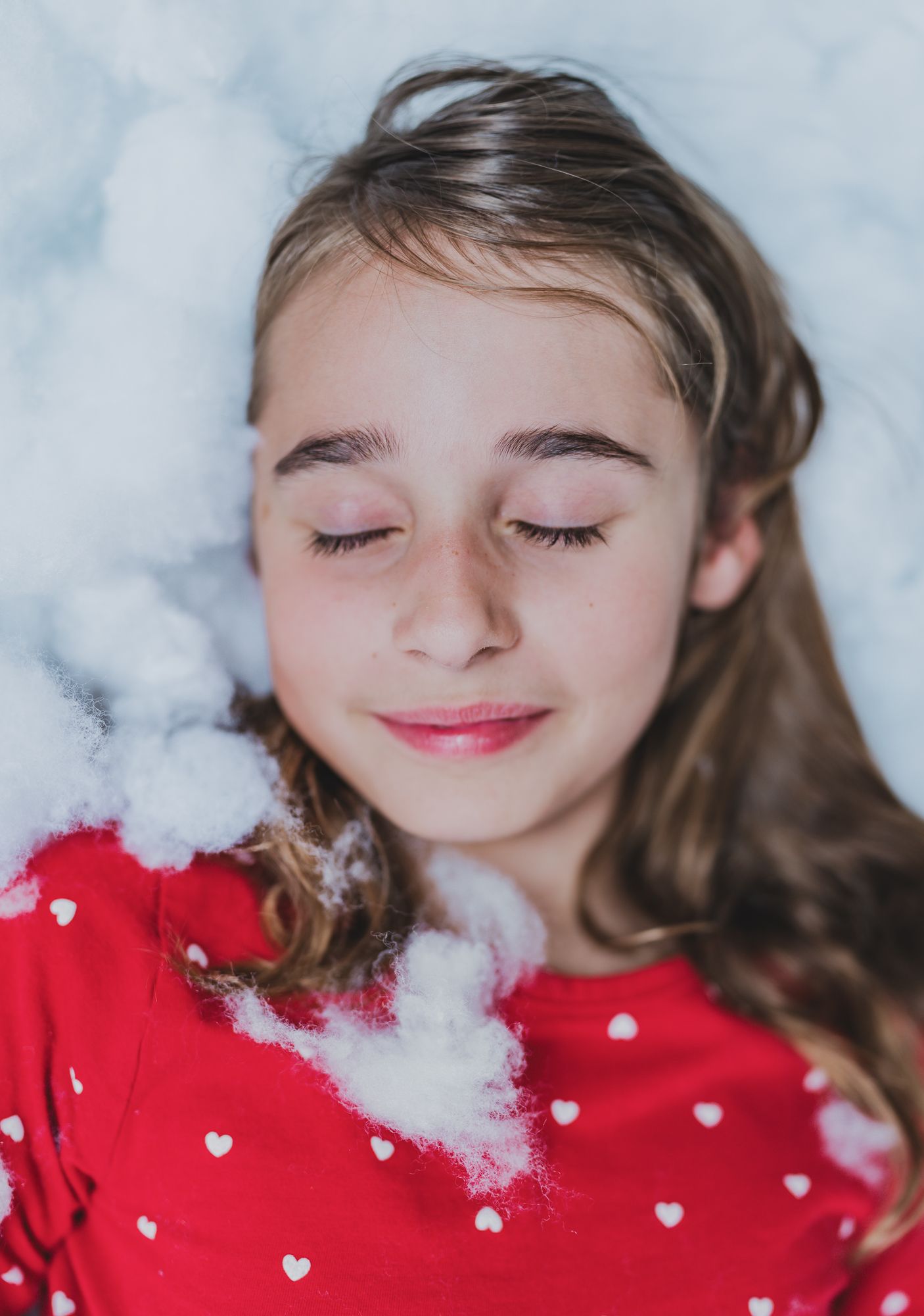 Two girls in matching red holiday pajamas laughing together while lying in faux snow during a winter photography session in Austin, Texas.