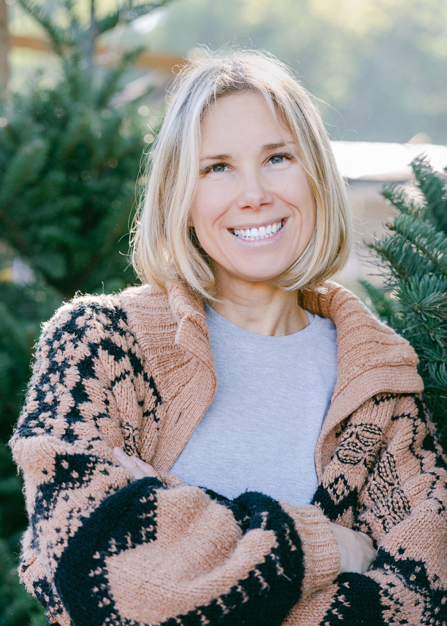 A portrait of a woman in front of christmas tress
