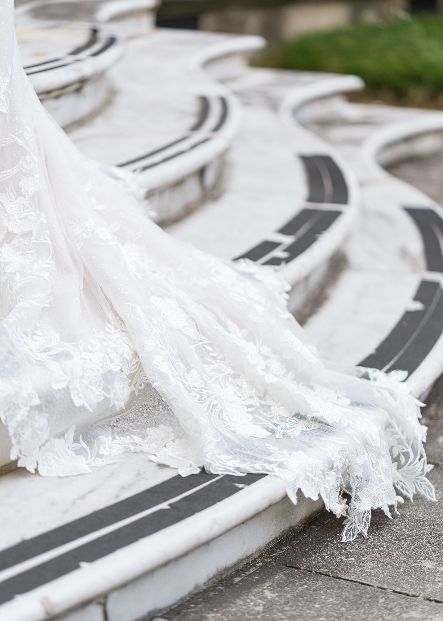 Lace wedding dress train cascading over curved stone steps.