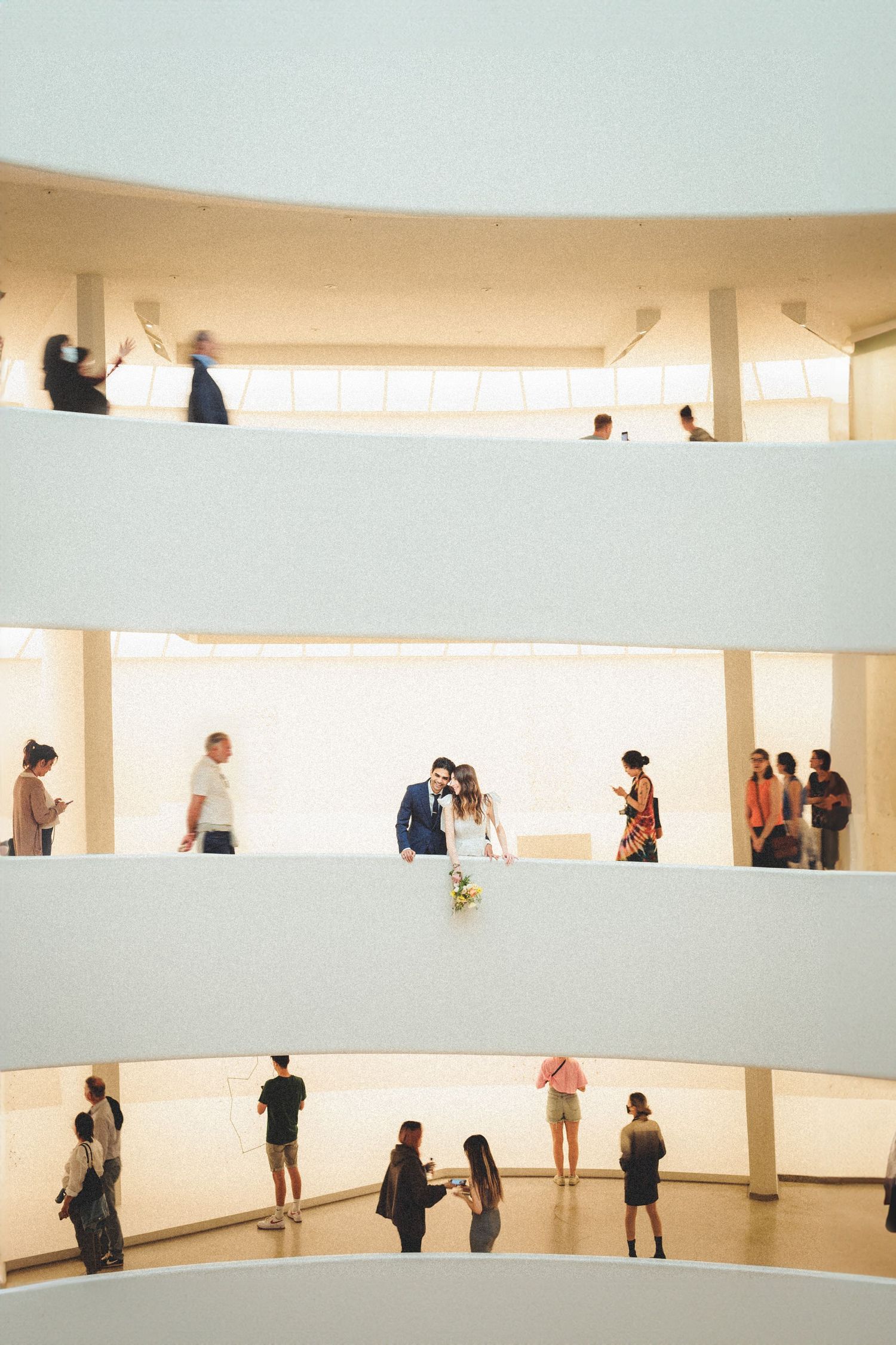 Couple shares a romantic moment on the spiral ramp of the Guggenheim Museum surrounded by visitors.