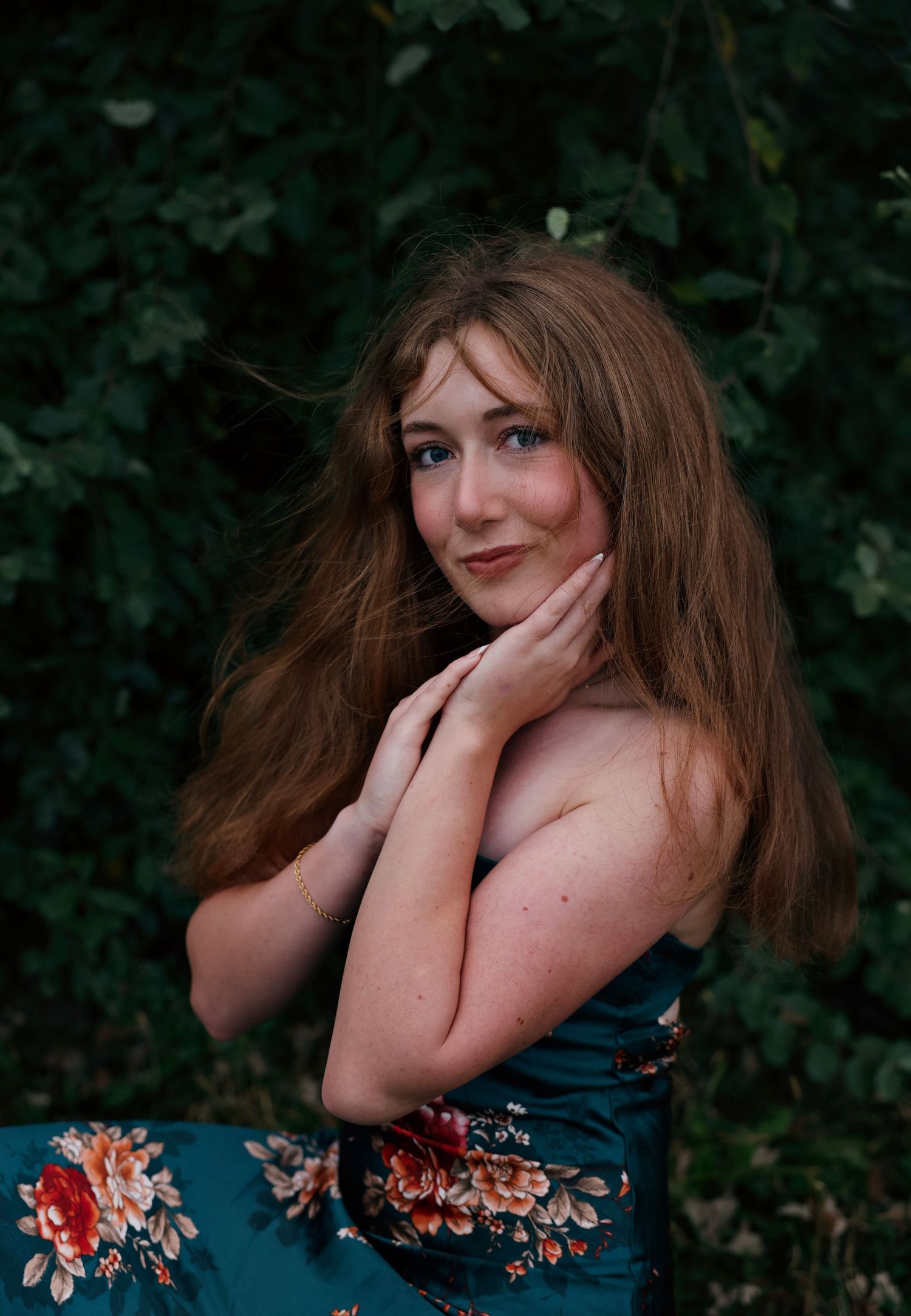 A portrait against green foliage shows someone in a blue floral dress with flowing brown hair in a romantic pose.