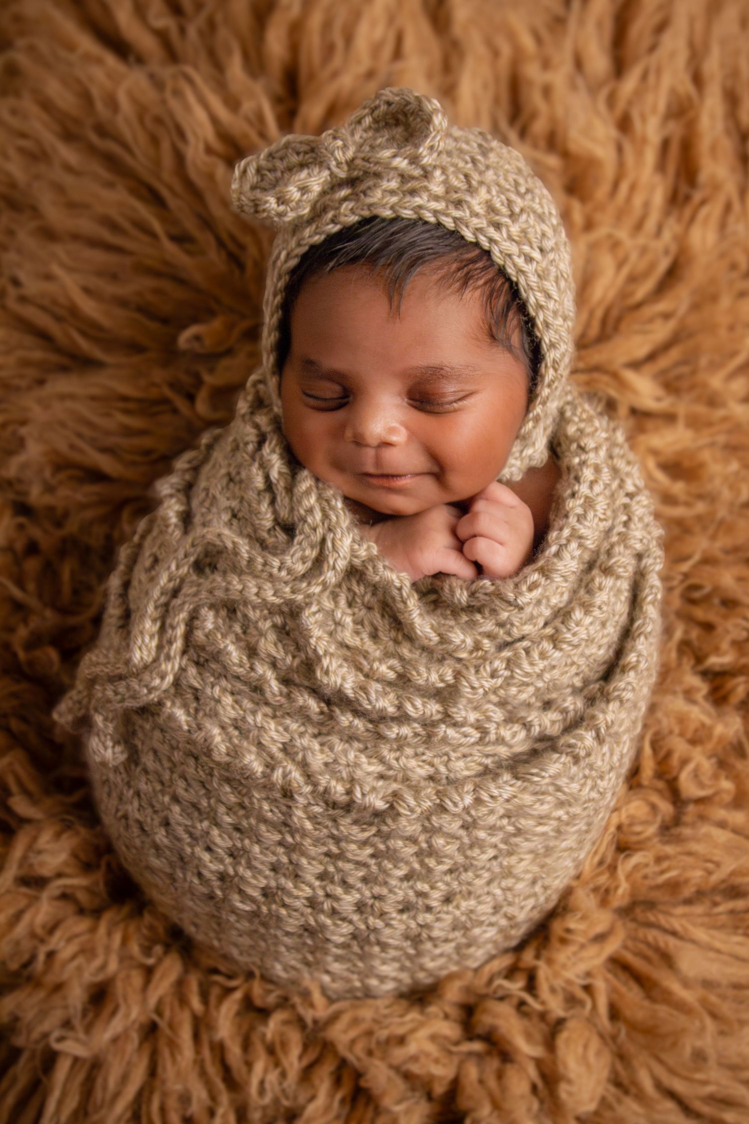 Smiling newborn in knit wrap