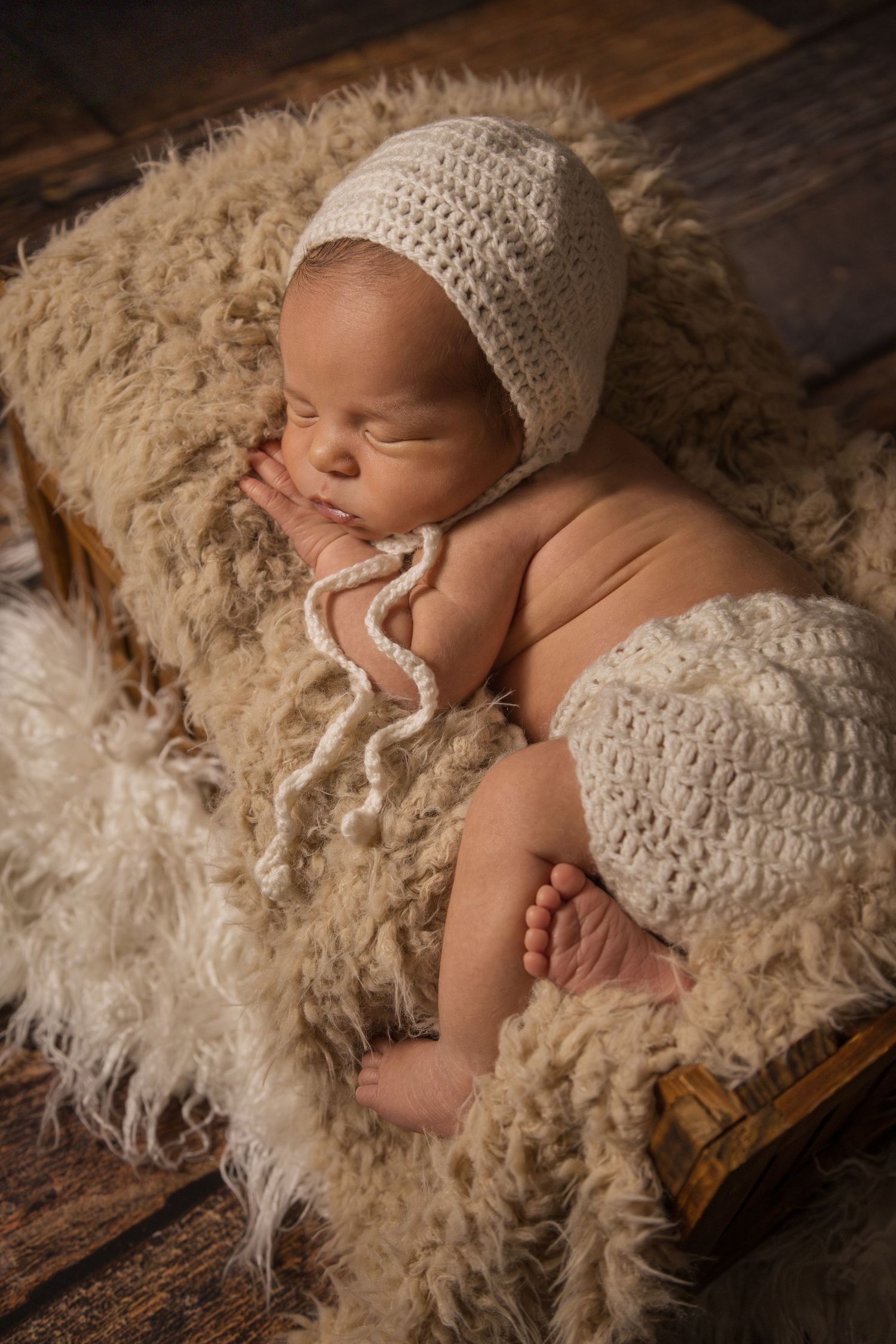 Sleepy newborn boy in fur bed