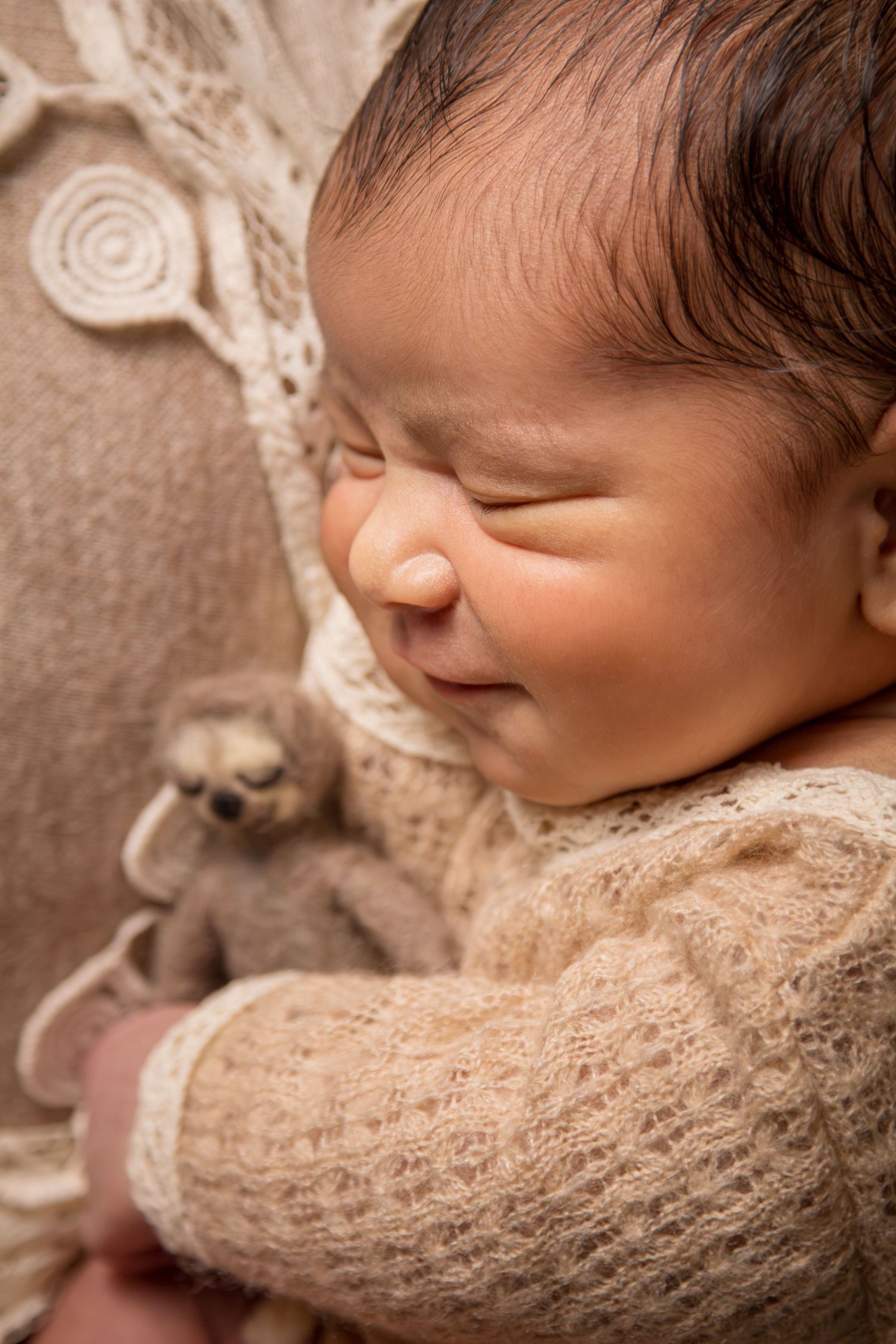 Smiling sleepy newborn holding sloth