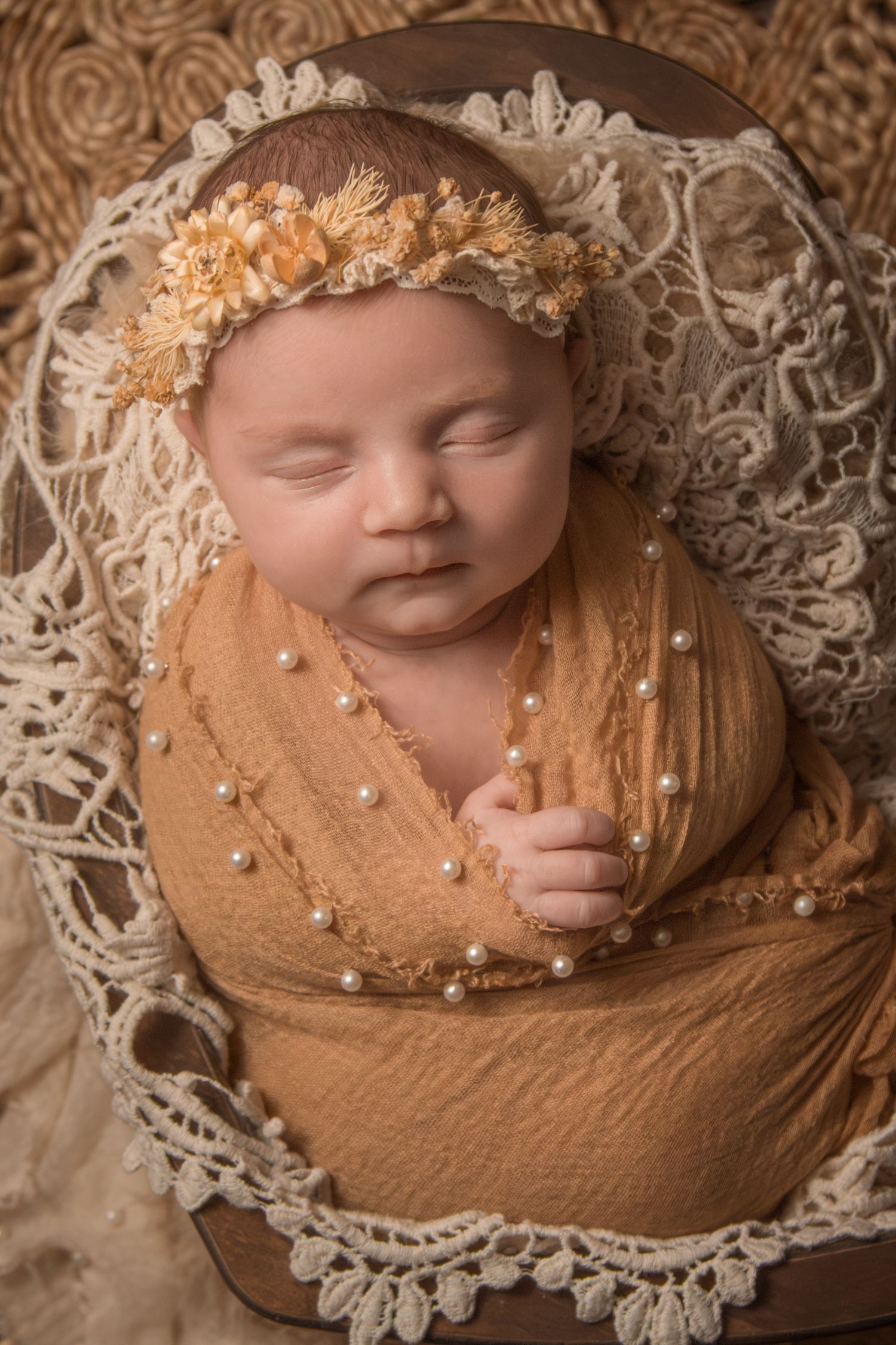 Sleepy newborn girl wrapped with boho headband