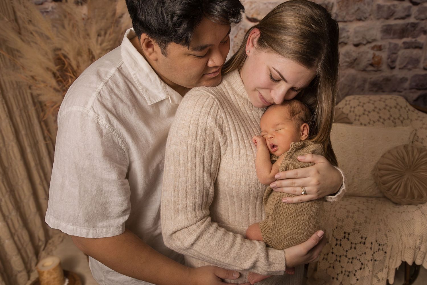 New family of three cuddled close in studio