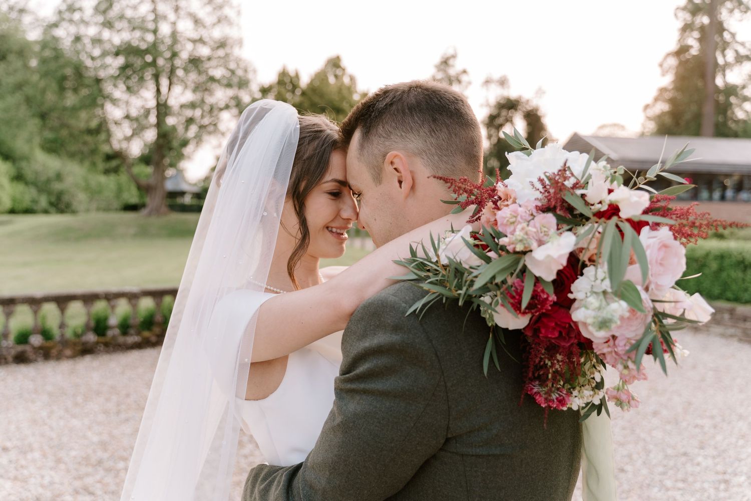 Romantic outdoor wedding scene with floral bouquet in soft pink and burgundy tones.