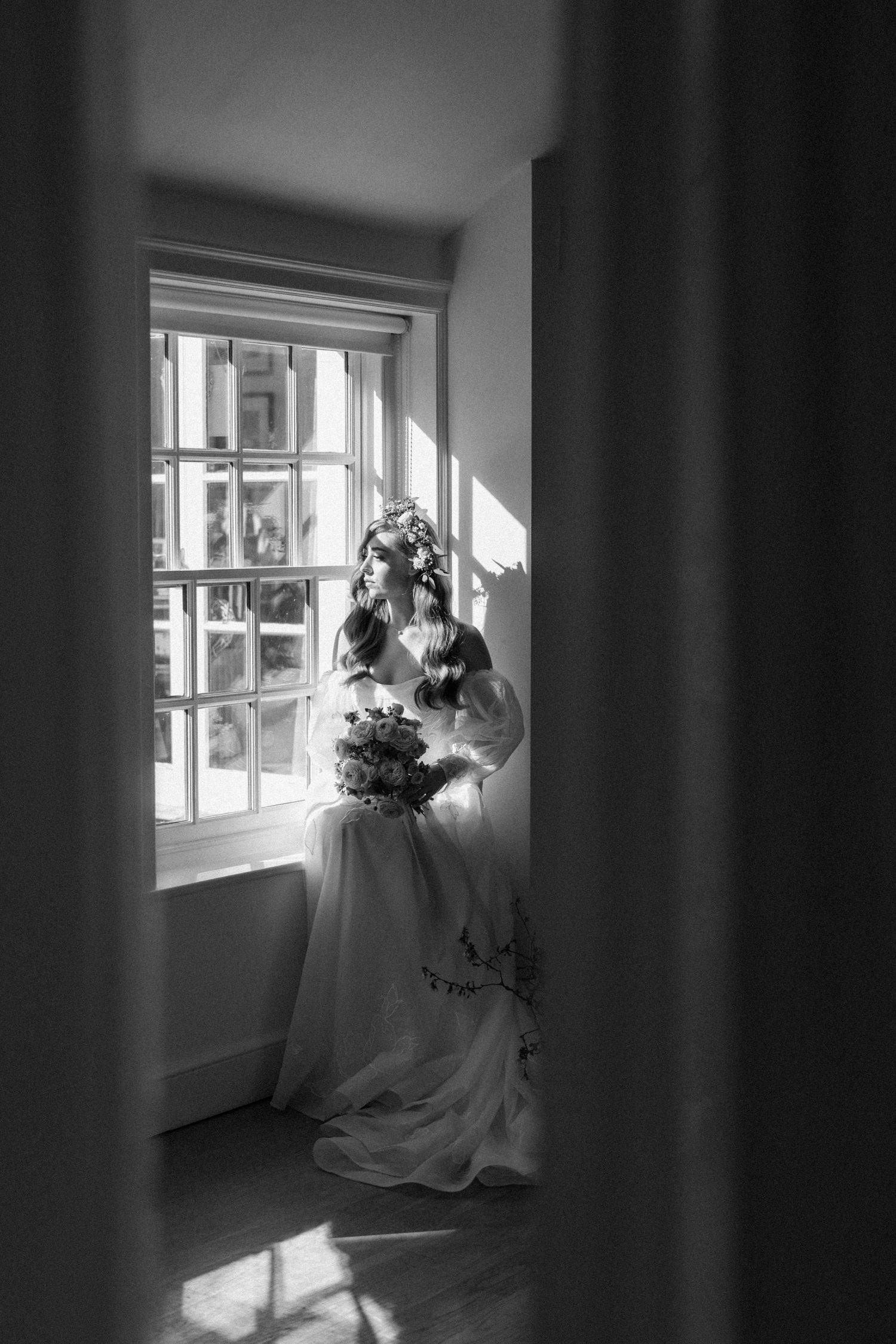 A series of black and white photographs showing a bridal gown and bouquet near a sunlit window creating dramatic shadows.