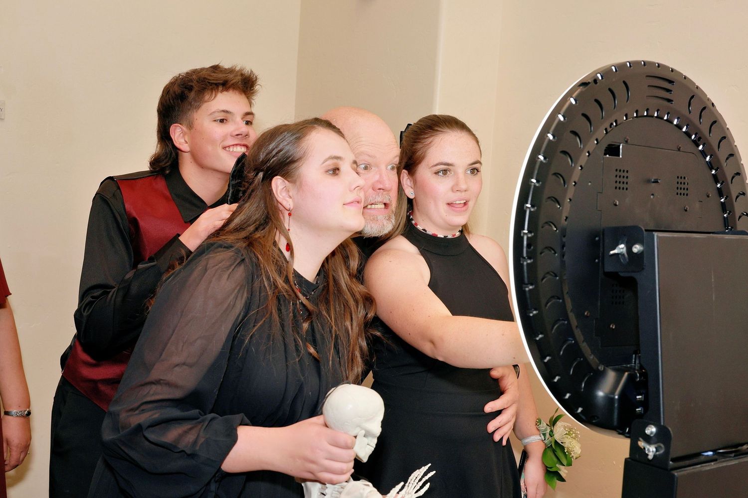 Group of four people posing together near a ring light at a formal event, smiling for a photo.