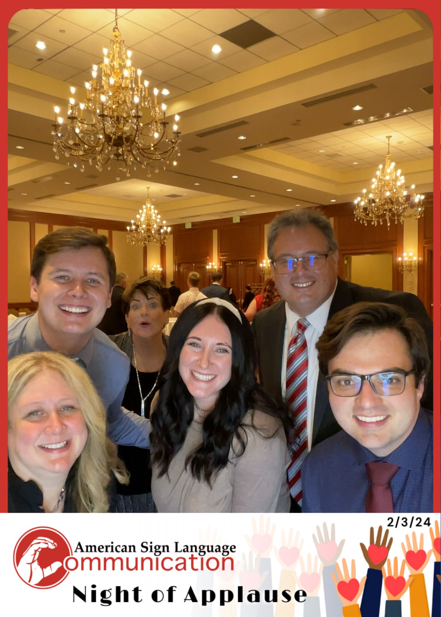 Group selfie at ASL Communication Night of Applause event on 2/3/24 in an elegant ballroom with chandeliers.