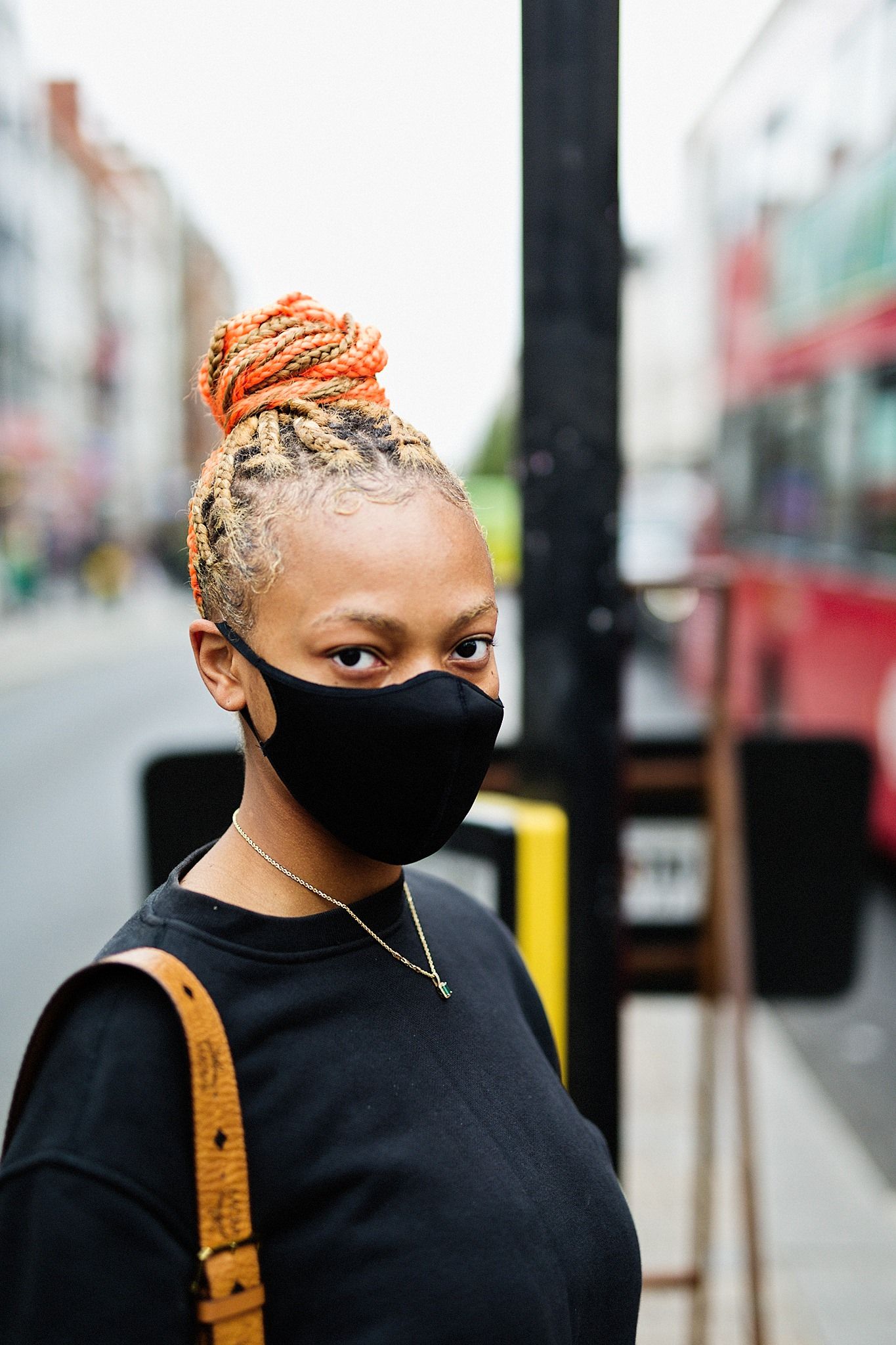 street portrait. Woman wearing covid mask. dreadlocks woven into bun.
