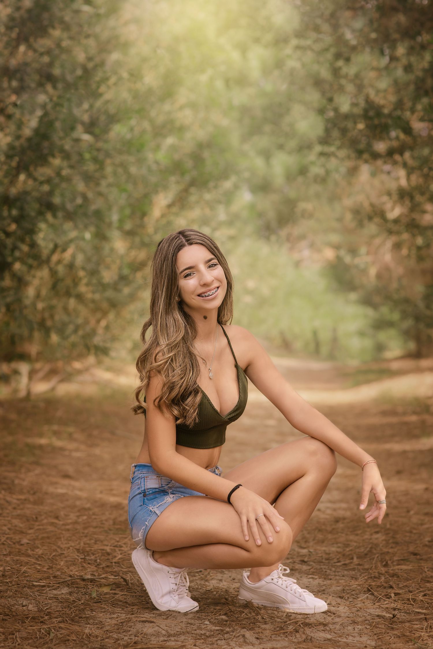 Outdoor portrait in a sunlit forest path with denim shorts and athletic wear creating a warm natural atmosphere.
