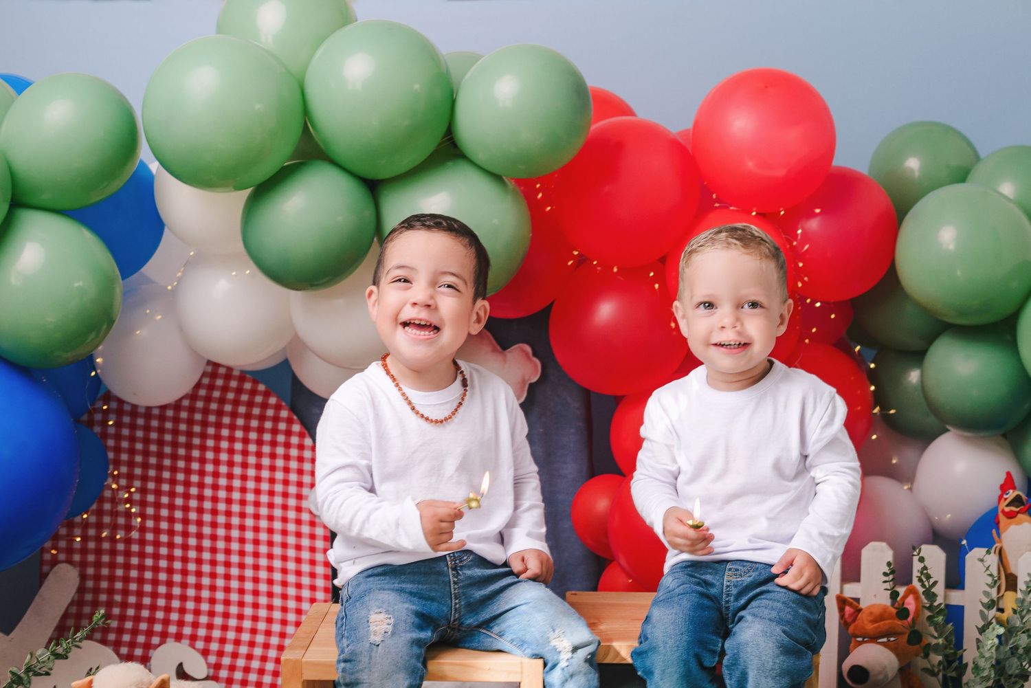 Children sit at a table with red and green balloon decorations during a festive holiday celebration.