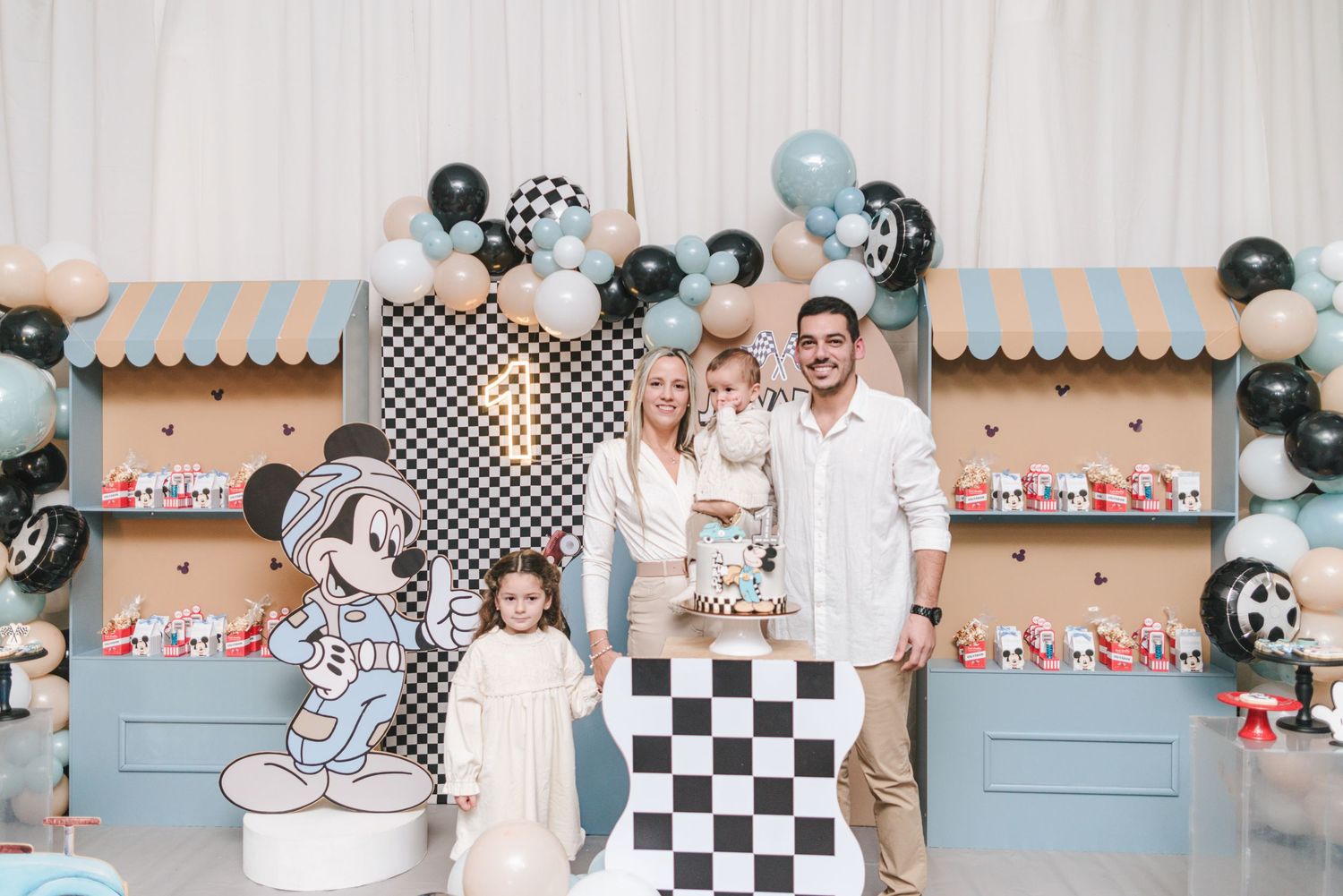 A racing themed birthday party setup with checkered flags, blue and orange decorations, and party tables.