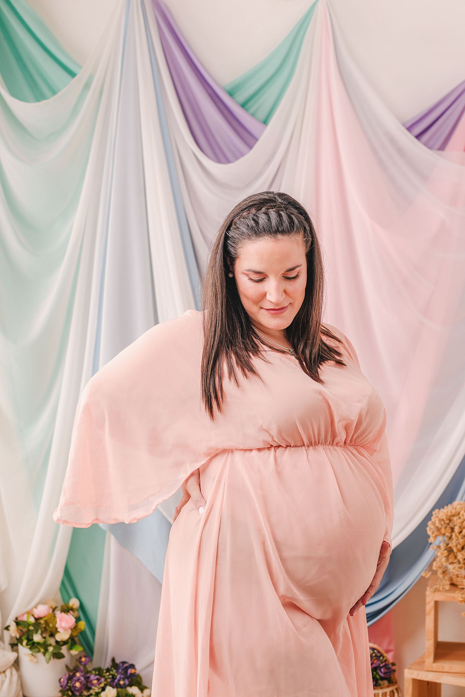 Maternity photo featuring pastel draped fabric backdrop.