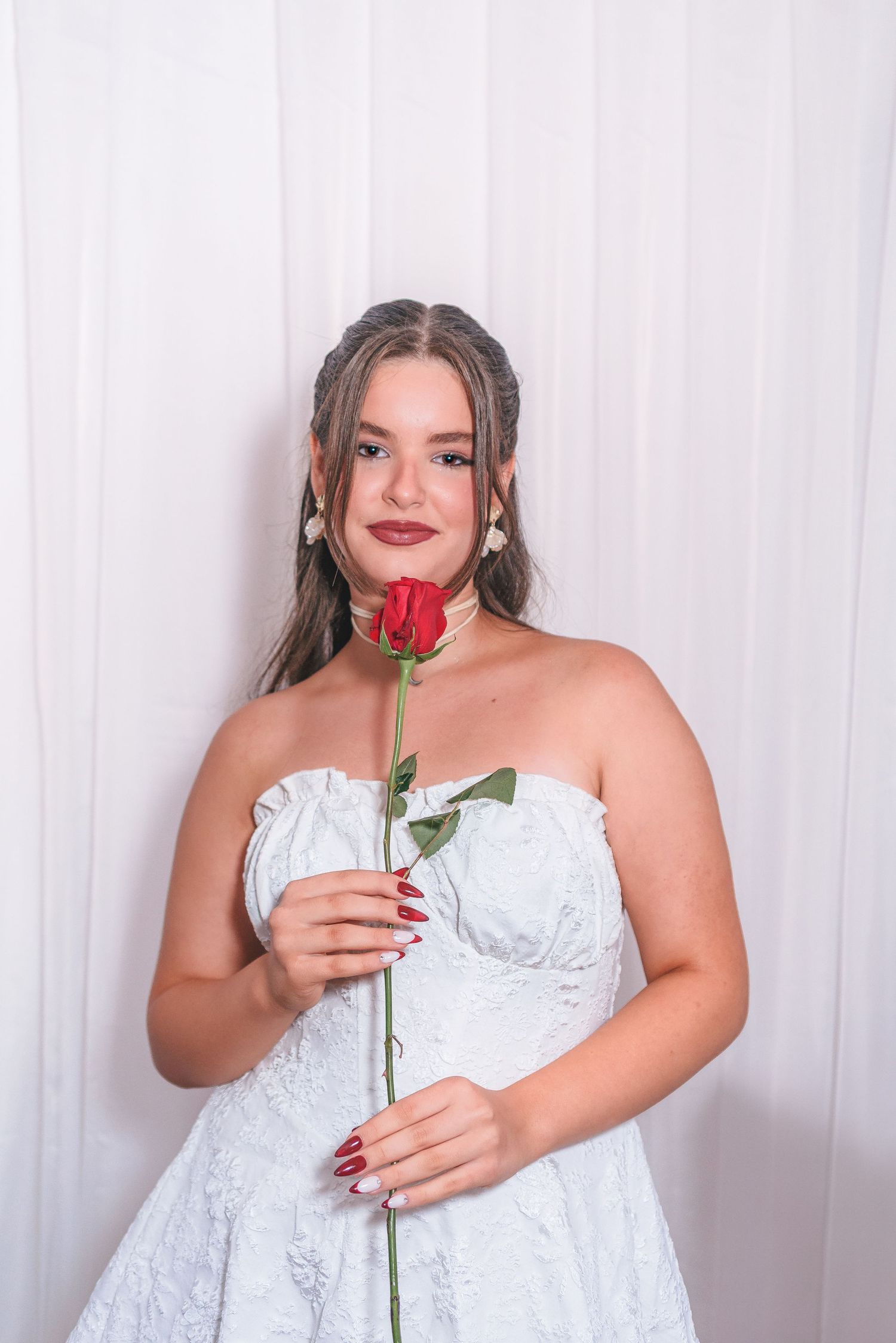 A series of three photos shows someone in a white lace dress holding a single red rose against a light background.