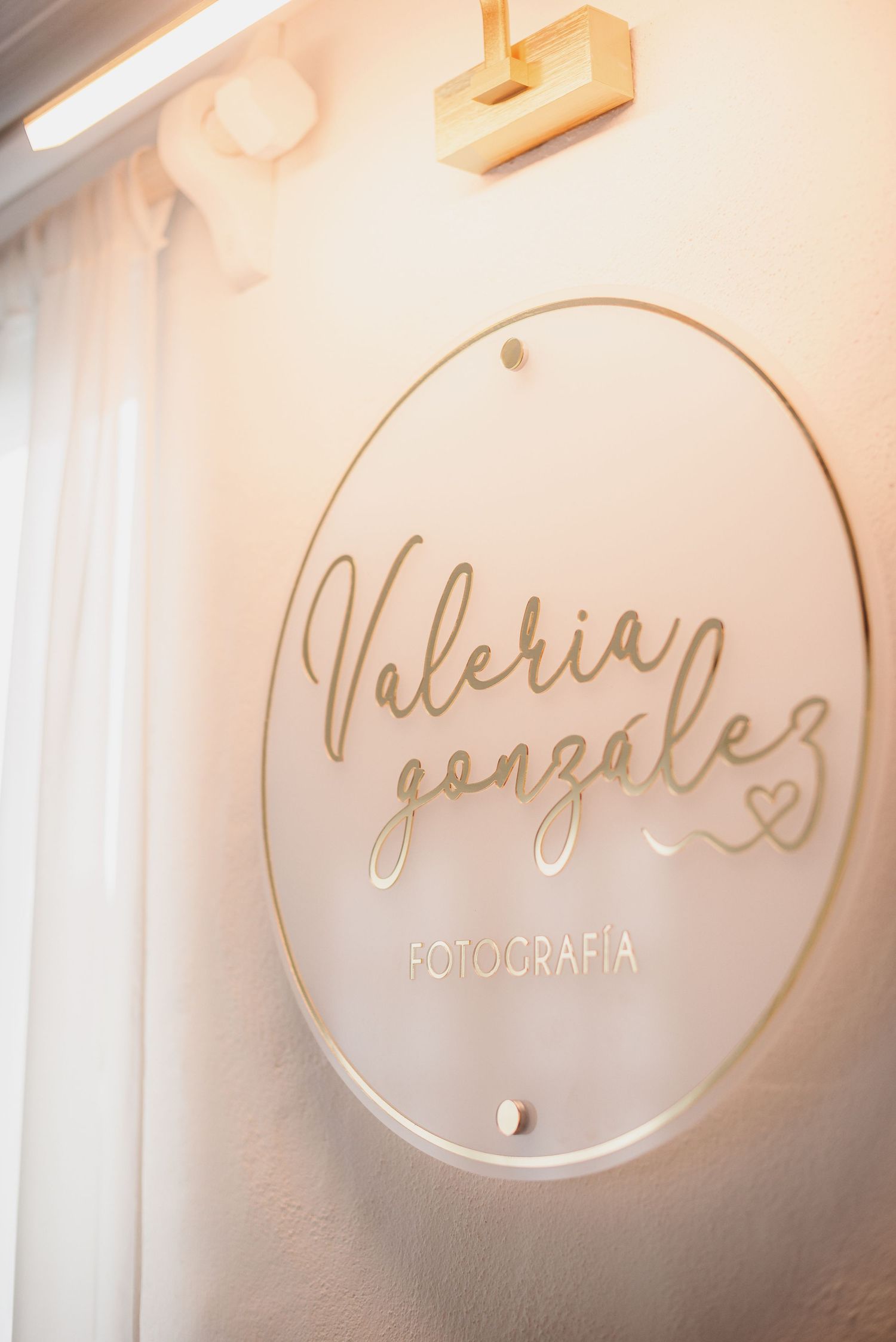 Circular acrylic sign with elegant script lettering mounted on white wall.