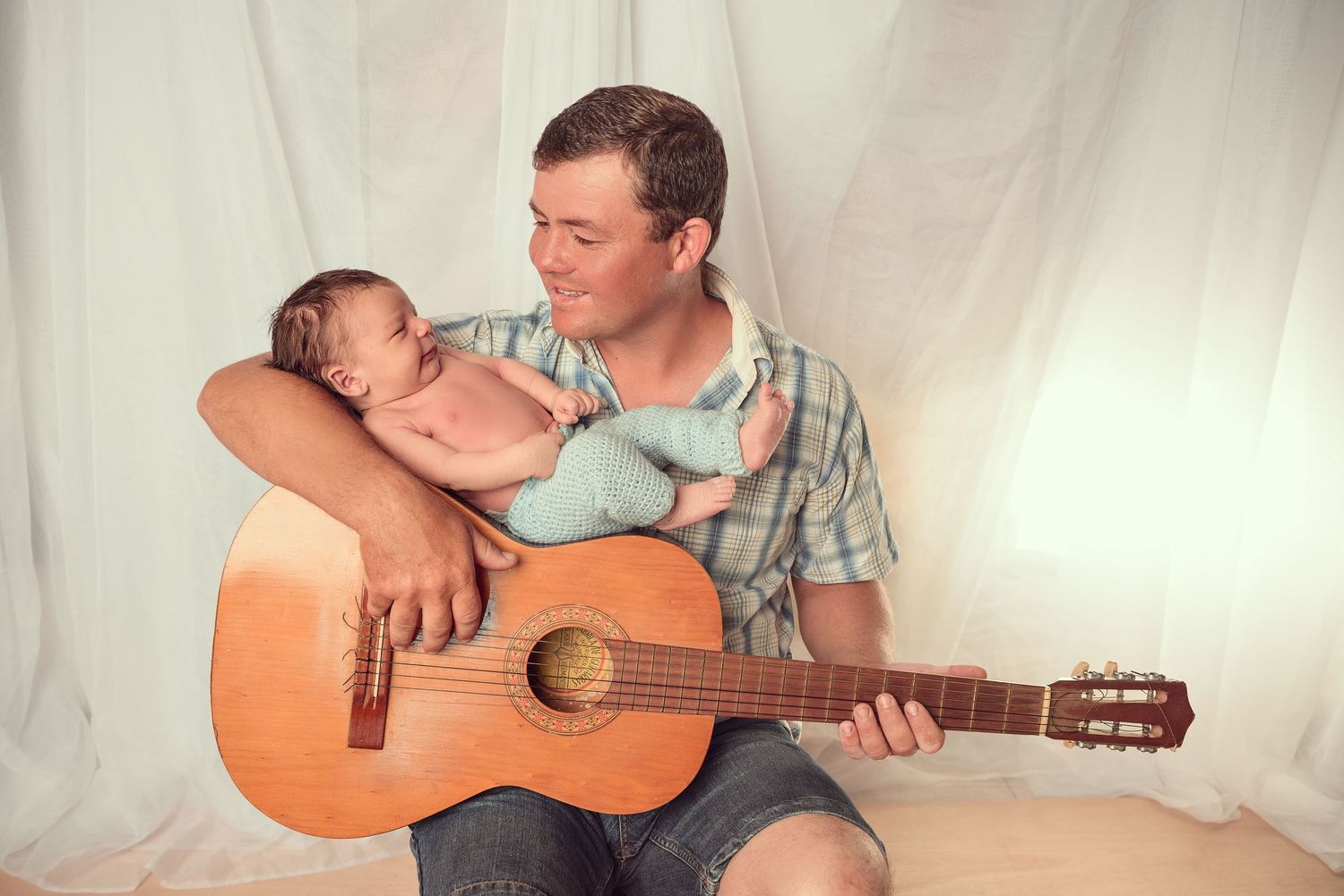 A series of four photos showing tender moments between a couple with an acoustic guitar against a white backdrop.