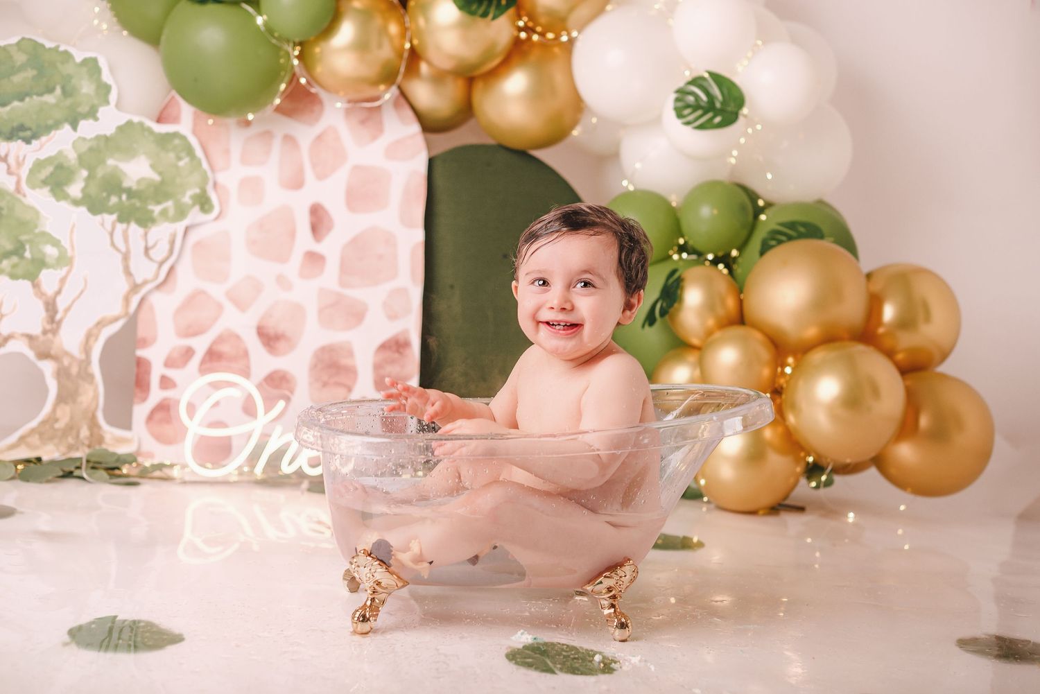 Festive party setup with gold and green balloons arranged against a pink backdrop for a celebration.
