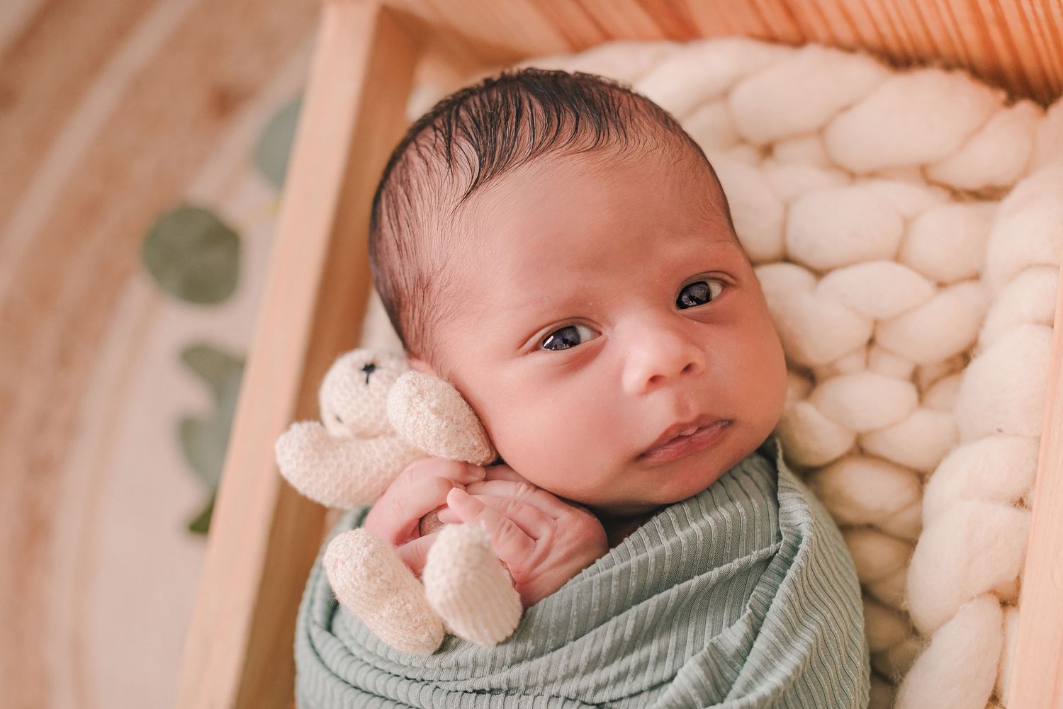 Professional newborn photography session featuring soft lighting and white cotton blankets.