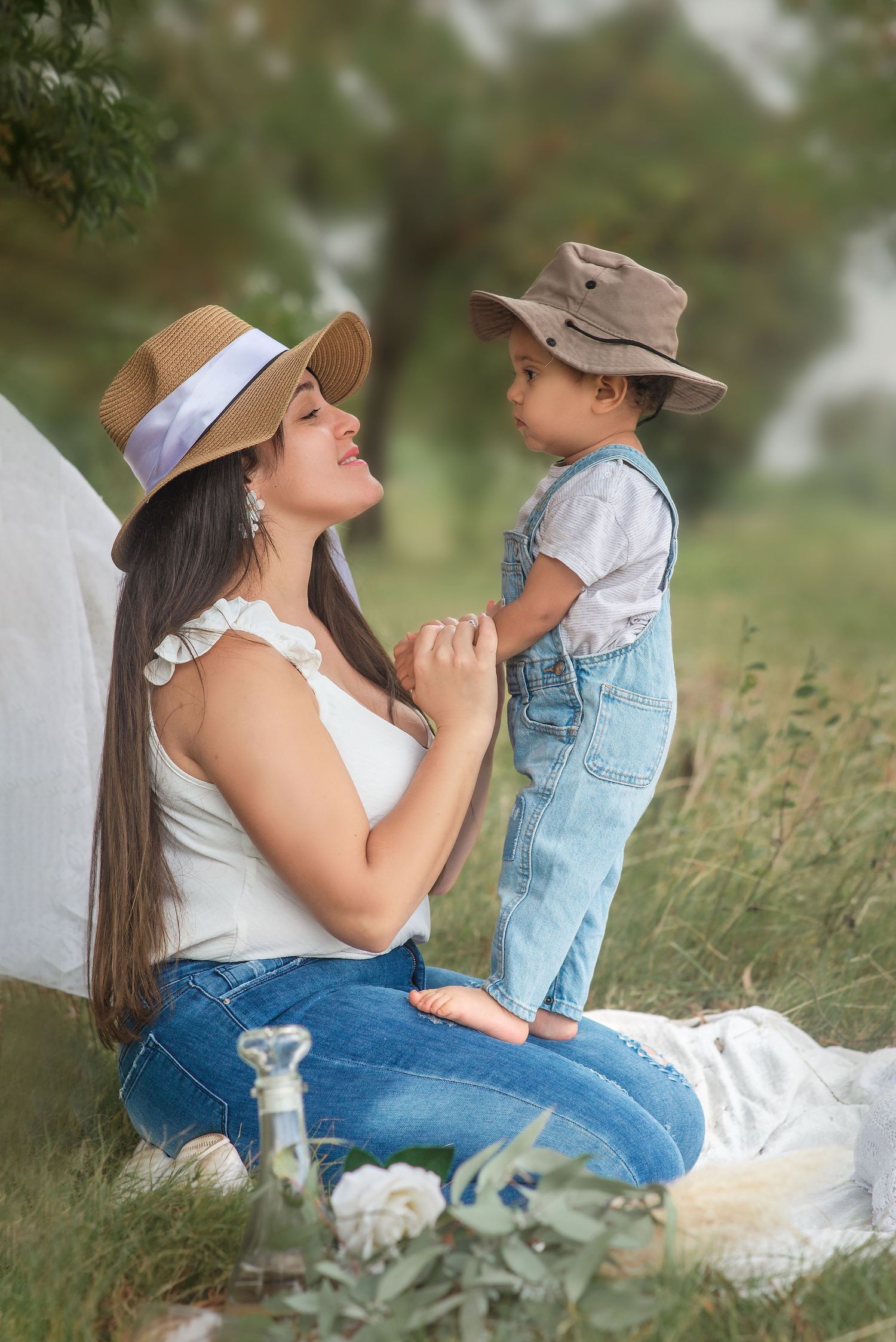 A tender outdoor moment shared between parent and child in matching denim on a grassy picnic blanket.