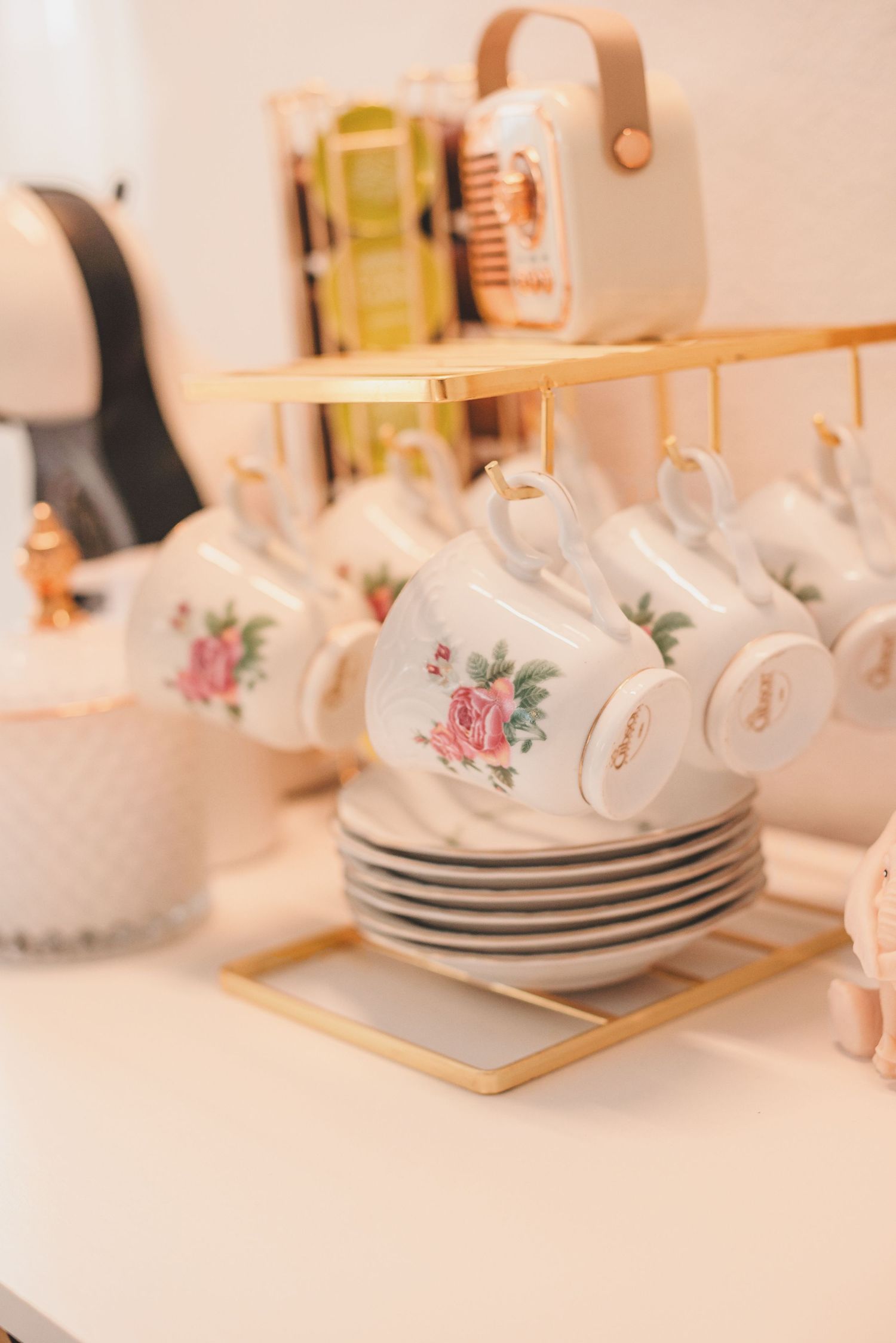 Delicate porcelain teacups with pink floral patterns arranged on white plates against a soft peach background.