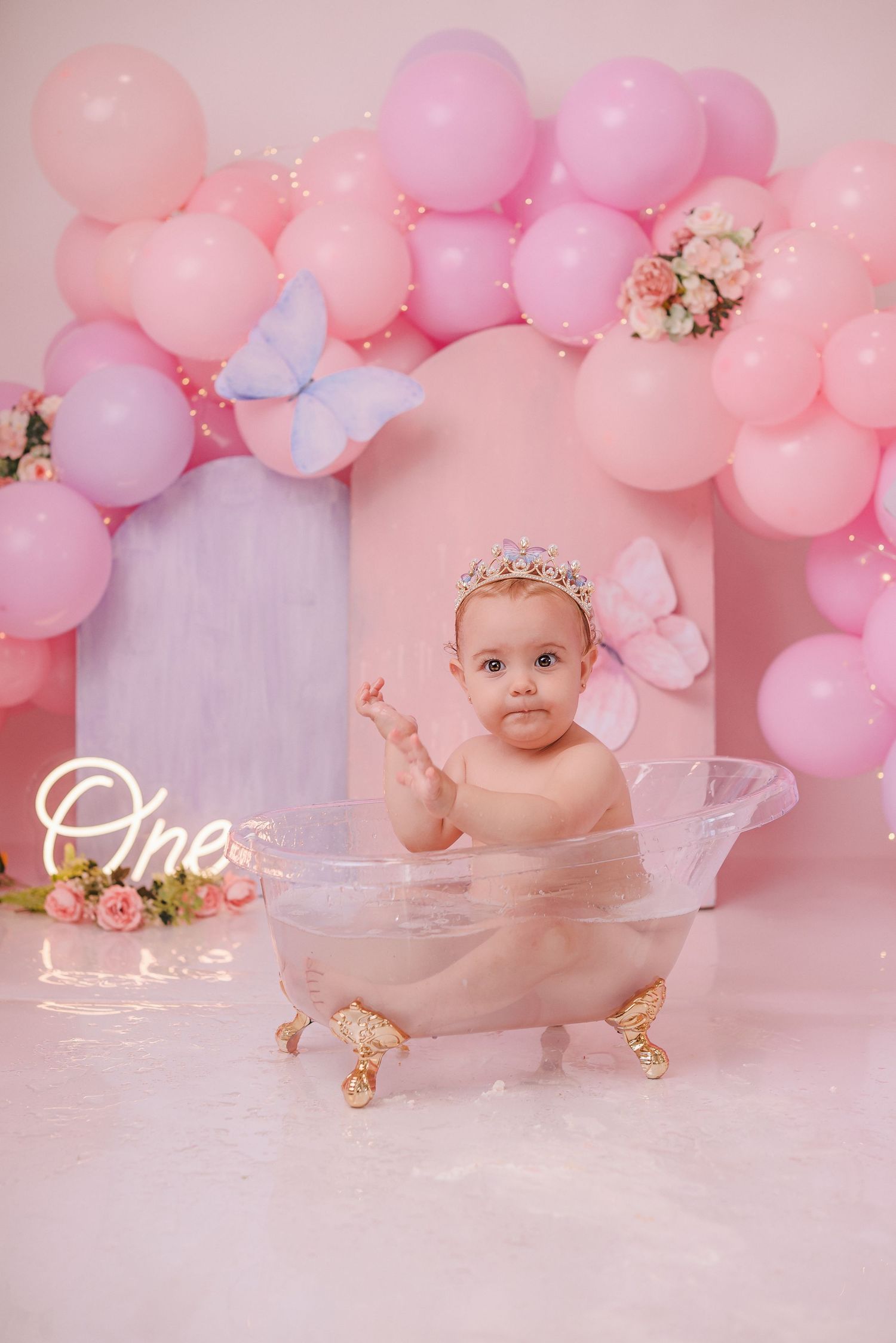 Pink balloon garland birthday setup with delicate floral accents and soft lighting.