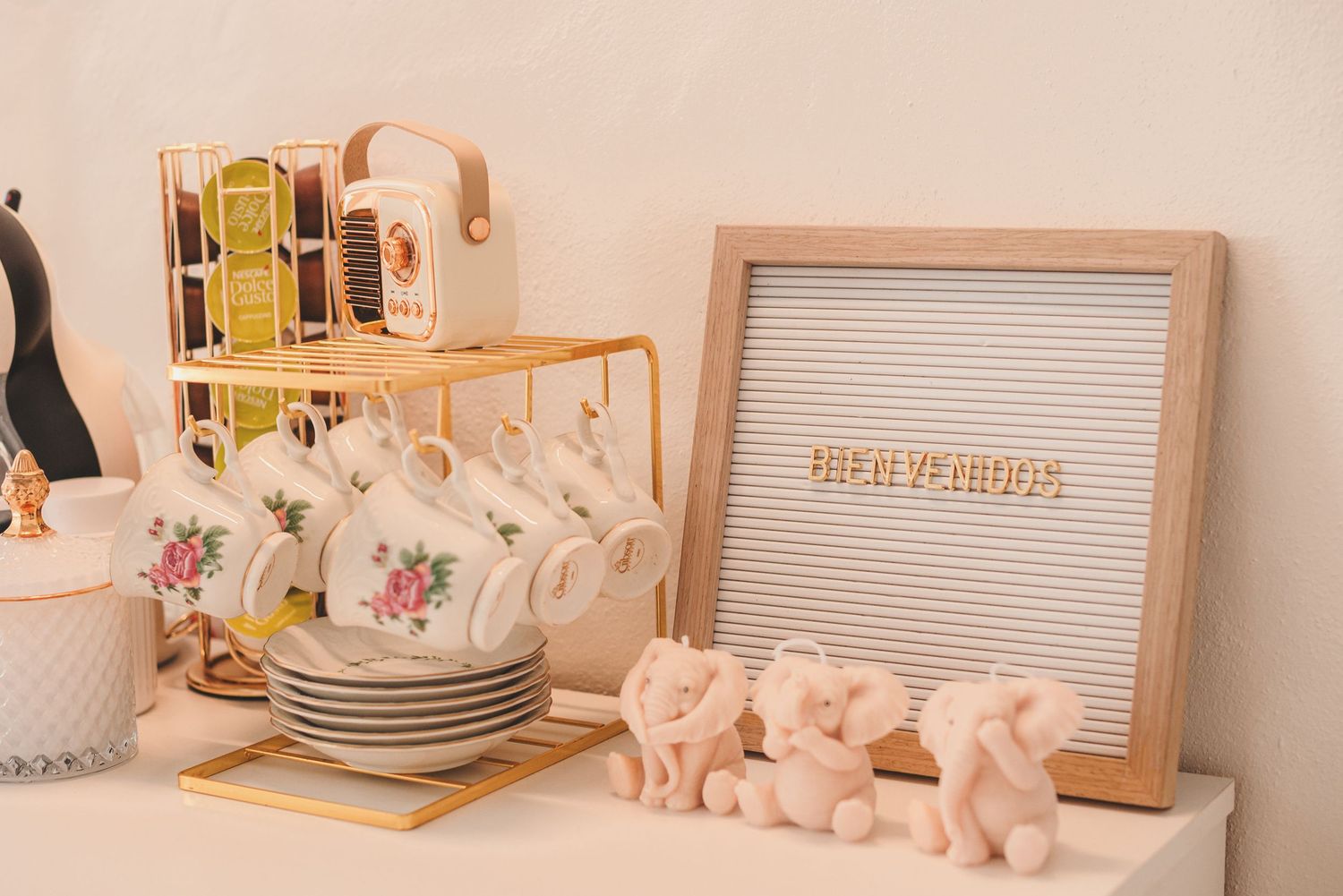 Pink and white ceramic tea set with delicate floral patterns displayed on wooden shelves with gold accents.
